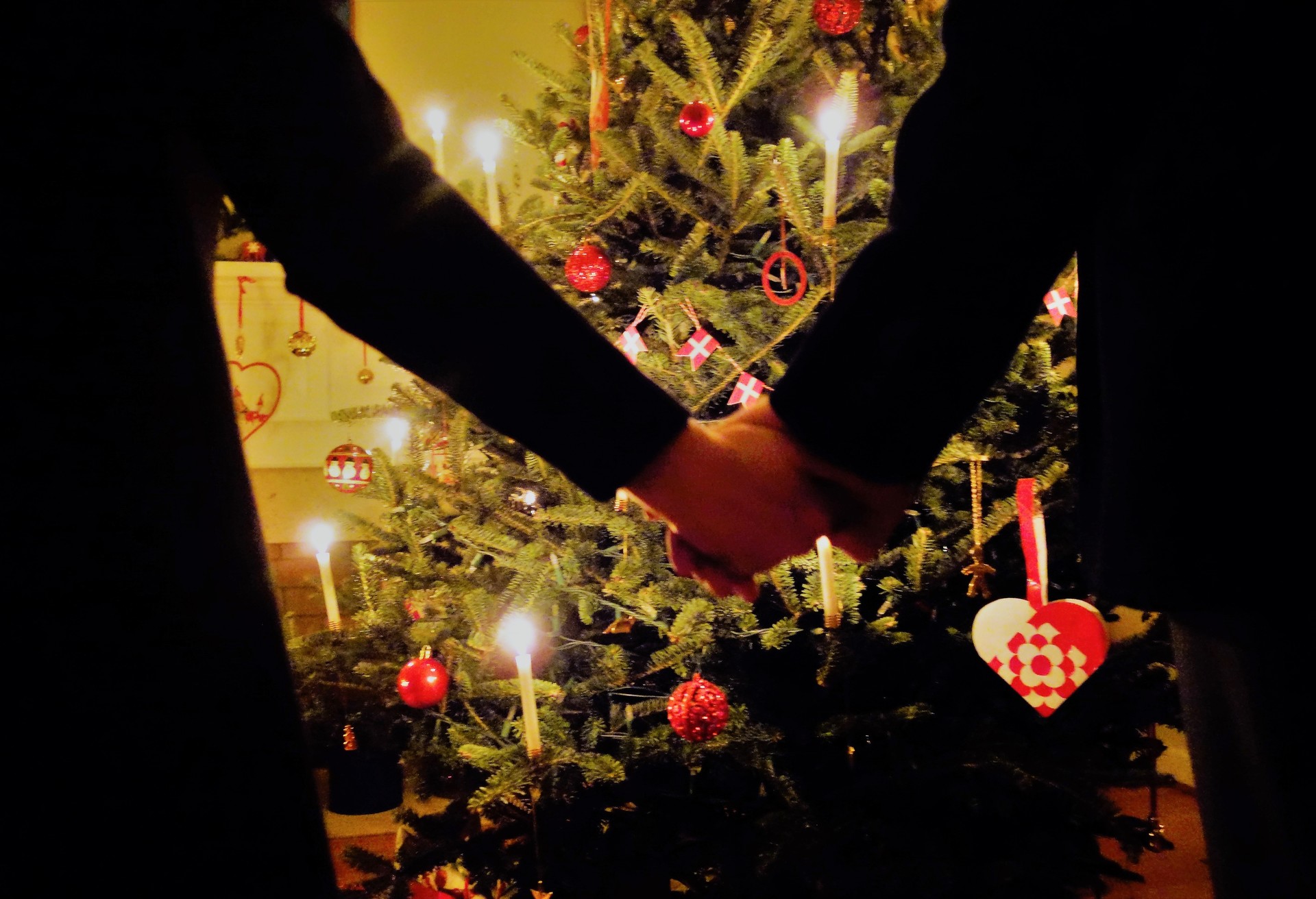 Friends  holding hands  while dancing  around the Christmas tree .