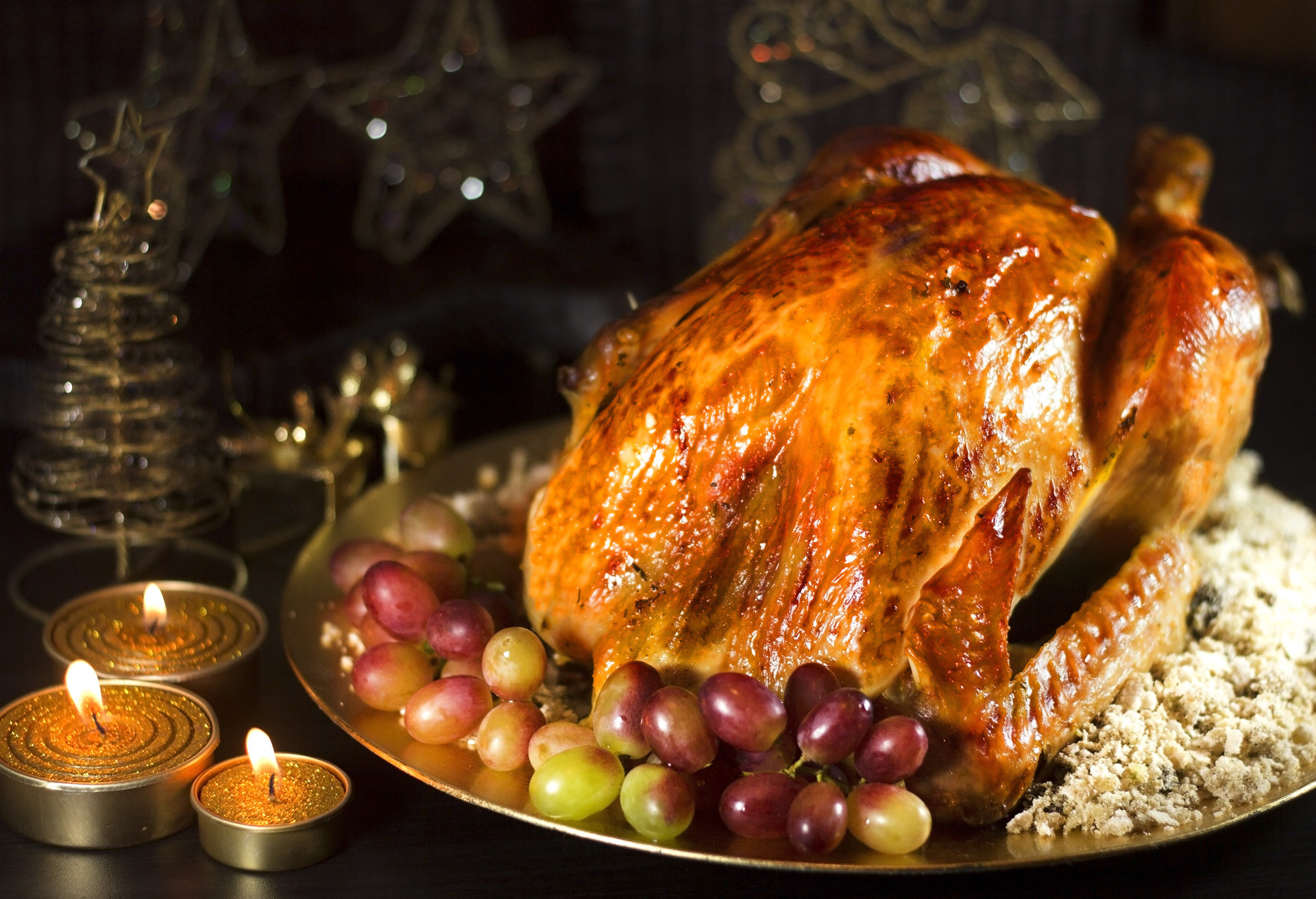 Roasted turkey with grapes and brazilian food farofa on dark background with candles.; Shutterstock ID 343312007; Purpose: Virtual Christmas Guides; Brand (KAYAK, Momondo, Any): Kayak; Client/Licensee: KAYAK