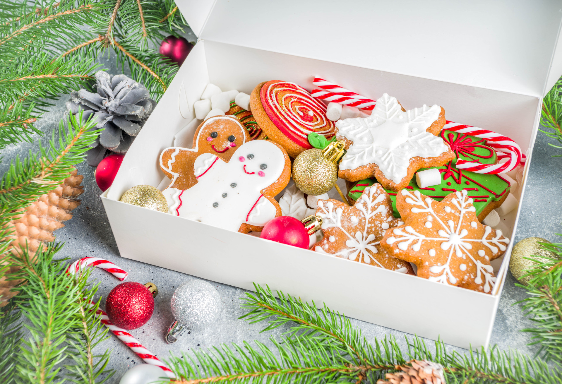 Homemade christmas sugar and gingerbread cookies decorated with colorful icing on grey stone background with Christmas tree branches and decorations; Shutterstock ID 1591003834; Purpose: Virtual Christmas Guides; Brand (KAYAK, Momondo, Any): Kayak; Client/Licensee: KAYAK