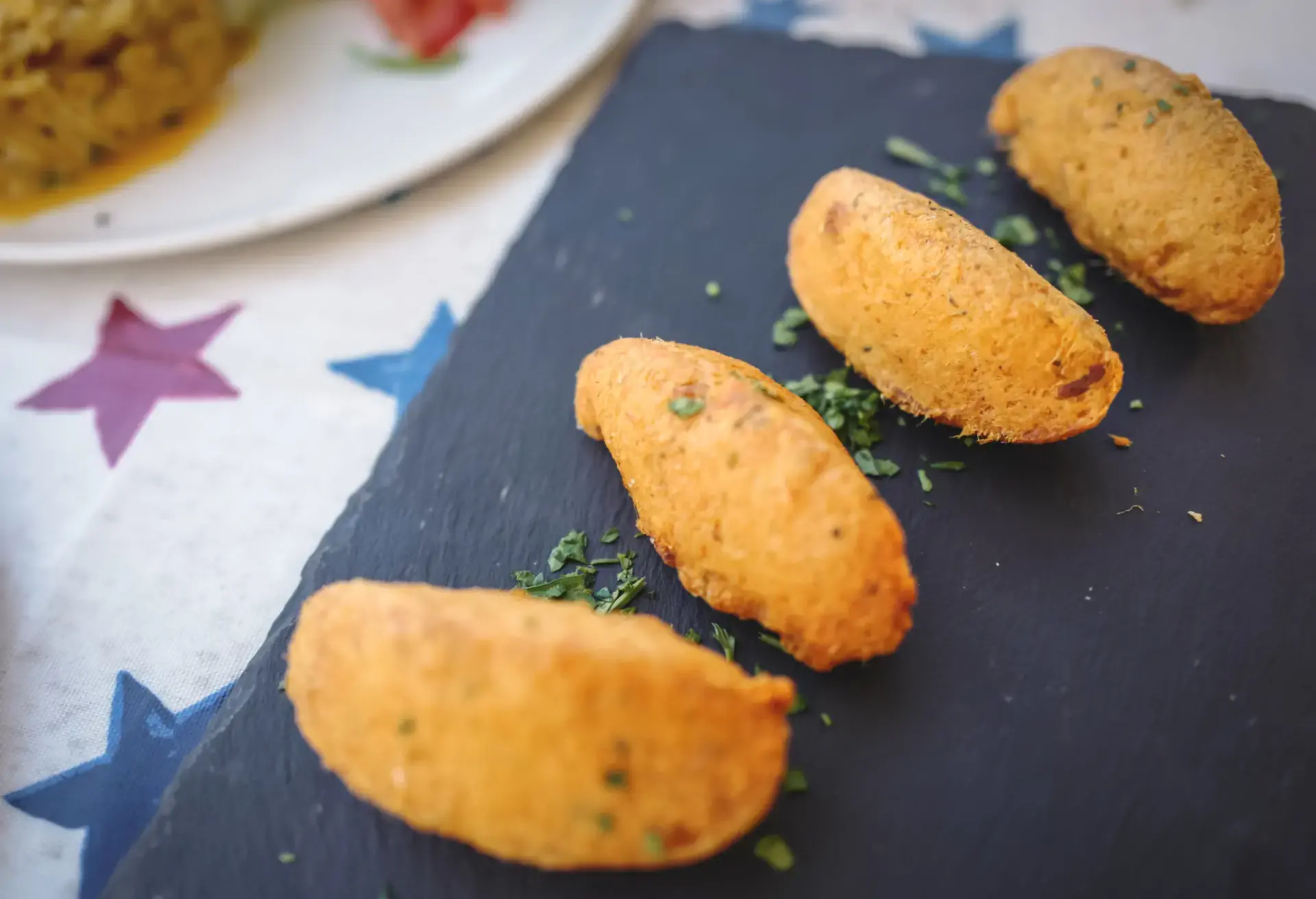4 Pastéis de bacalhau on a black slate