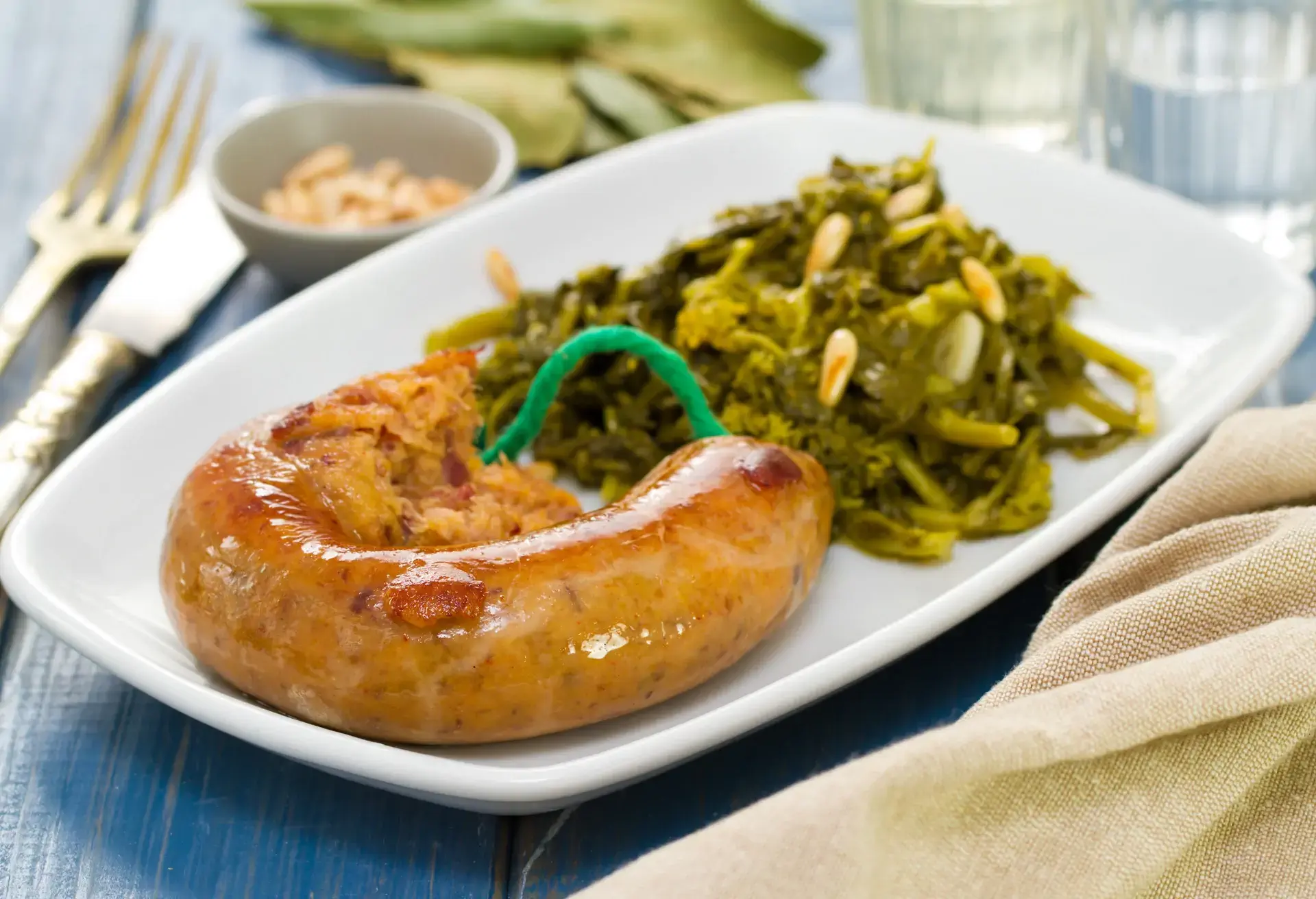 Alheira de Mirandela sausage on a white plate with green vegetables