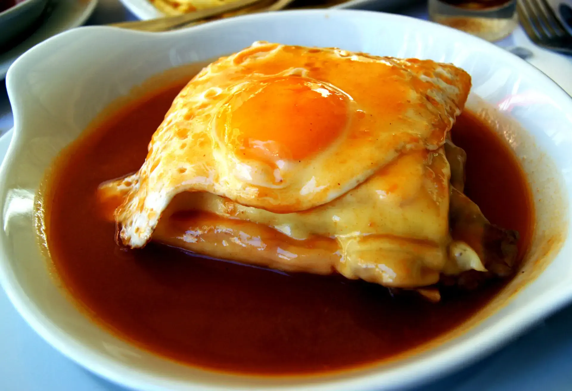 Francesinha with egg in a white deep dish