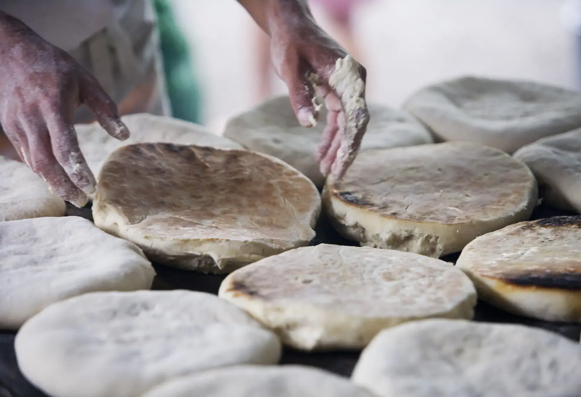 Hands turning Bolo do caco, a Madeira garlic bread