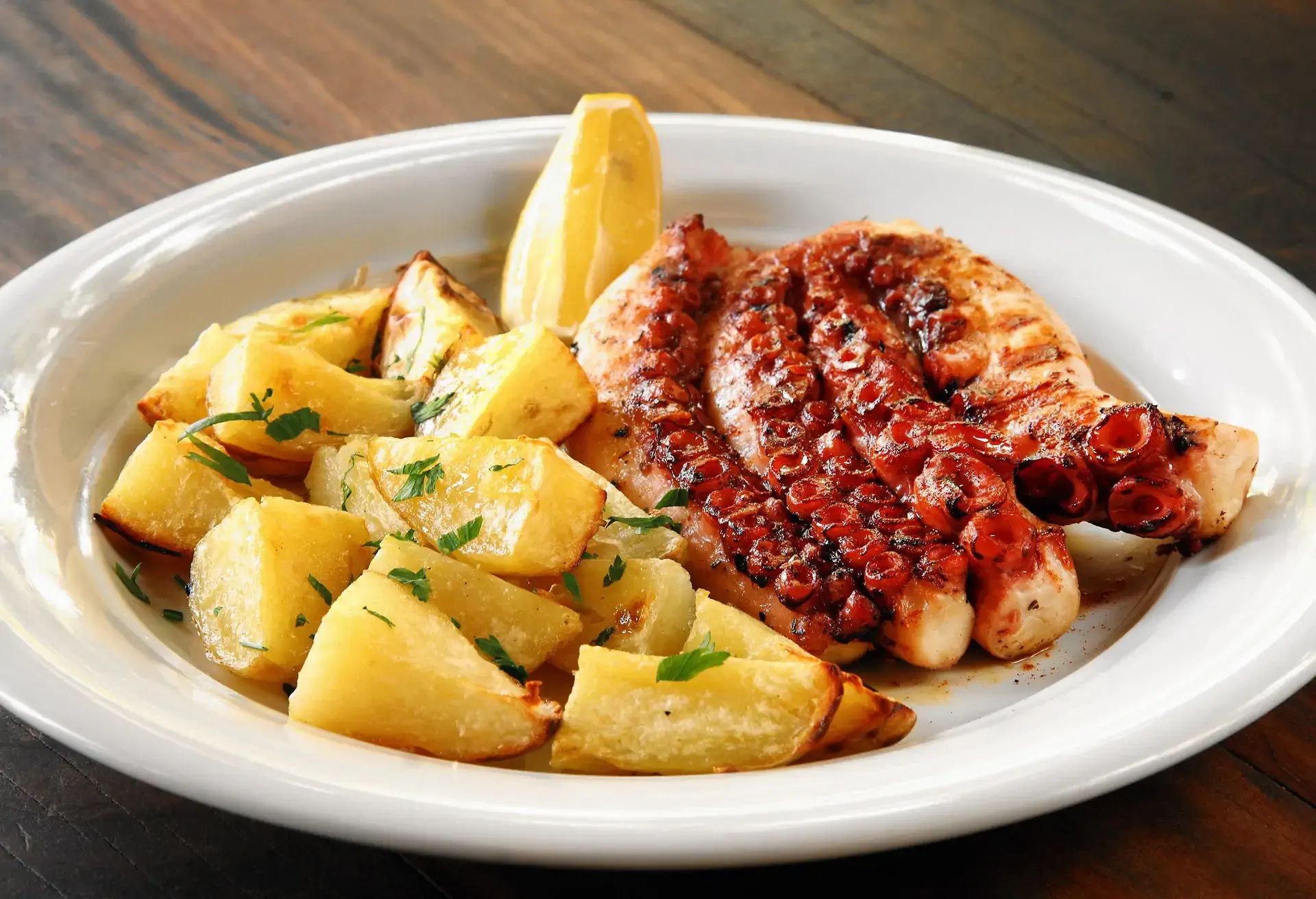 Polvo à Lagareiro grilled octopus with grilled potatoes on a white plate