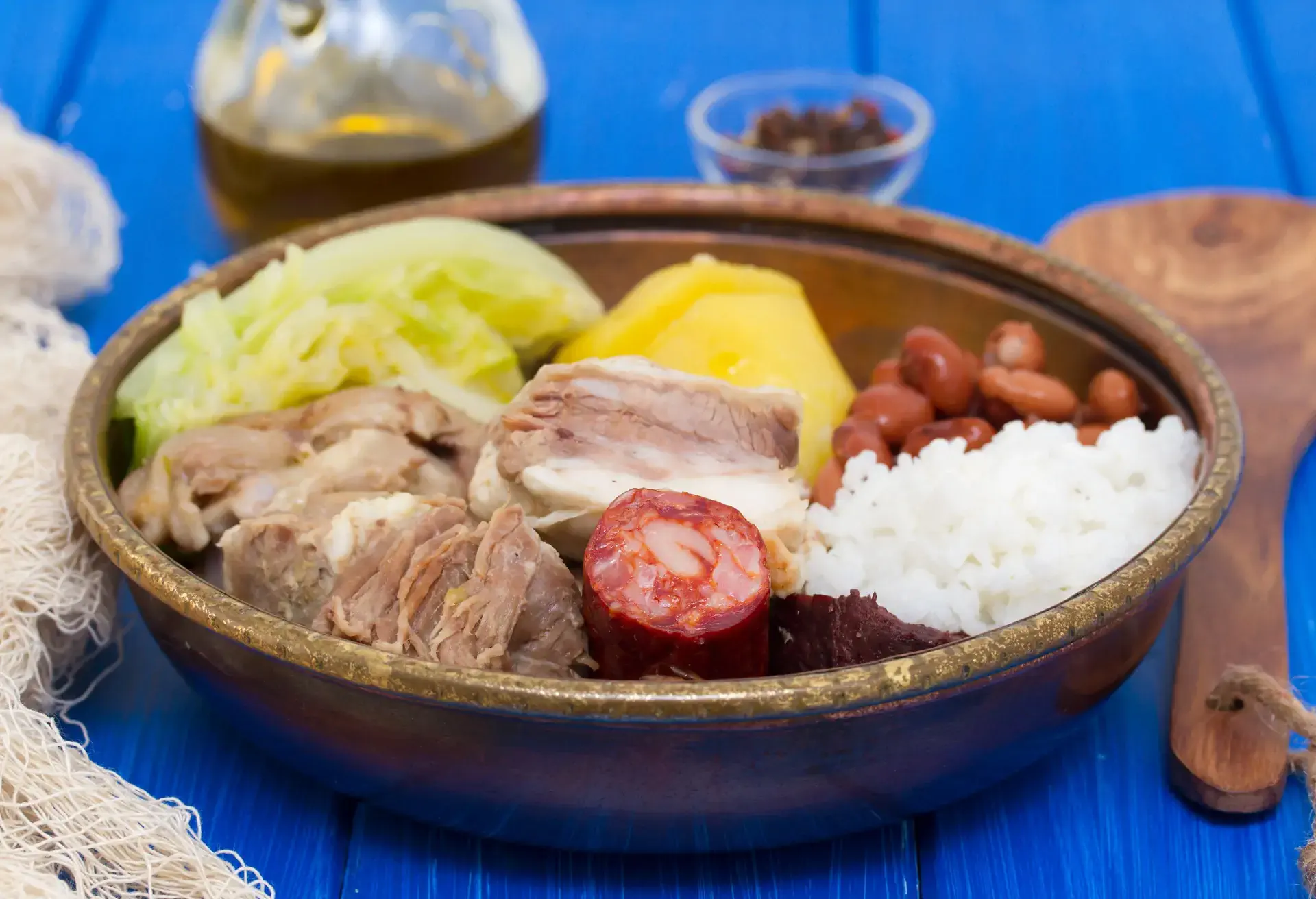 Cozido à portuguesa in a brown dish on a blue table