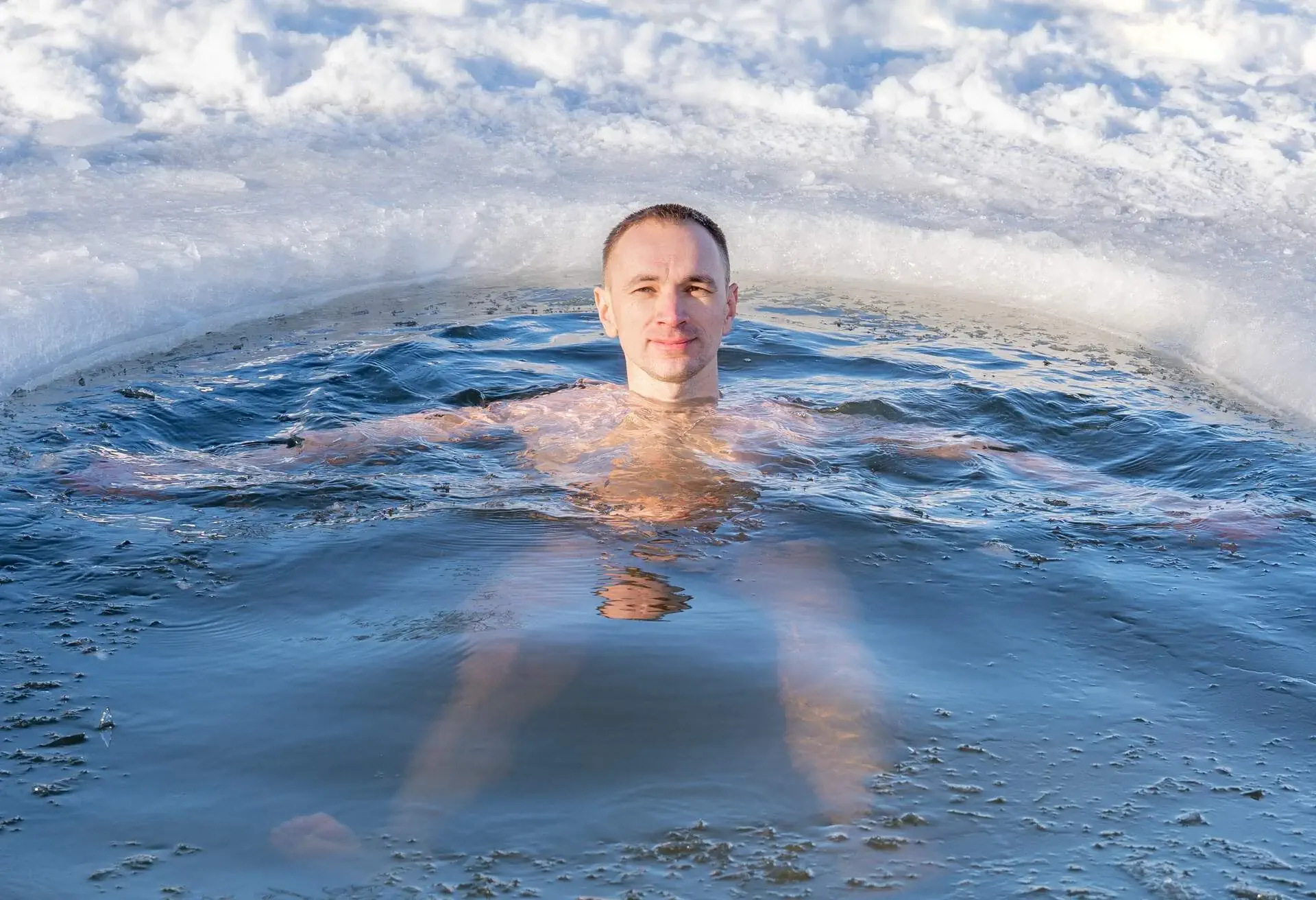 Portrait of man swimming in winter in the cold water of a lake surrounded by ice