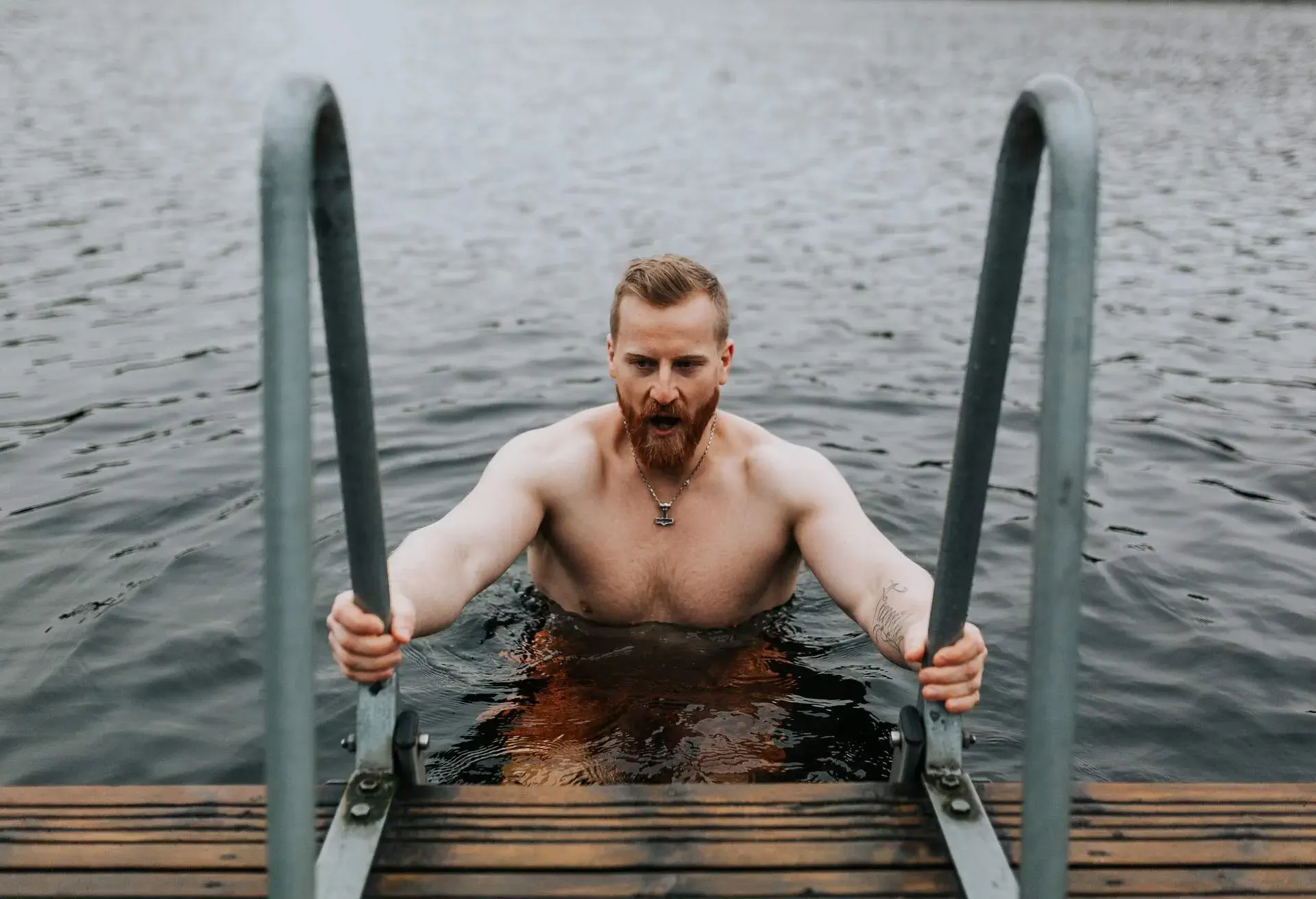Bearded man winter bathing in cold water on an overcast day
