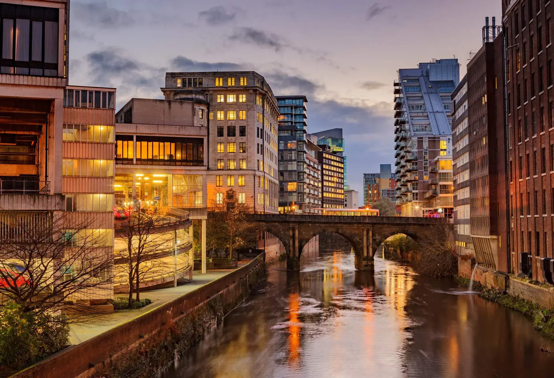 Manchester city in the autumn with sky scrapers in the distance and a quaint bridge at the forefront 