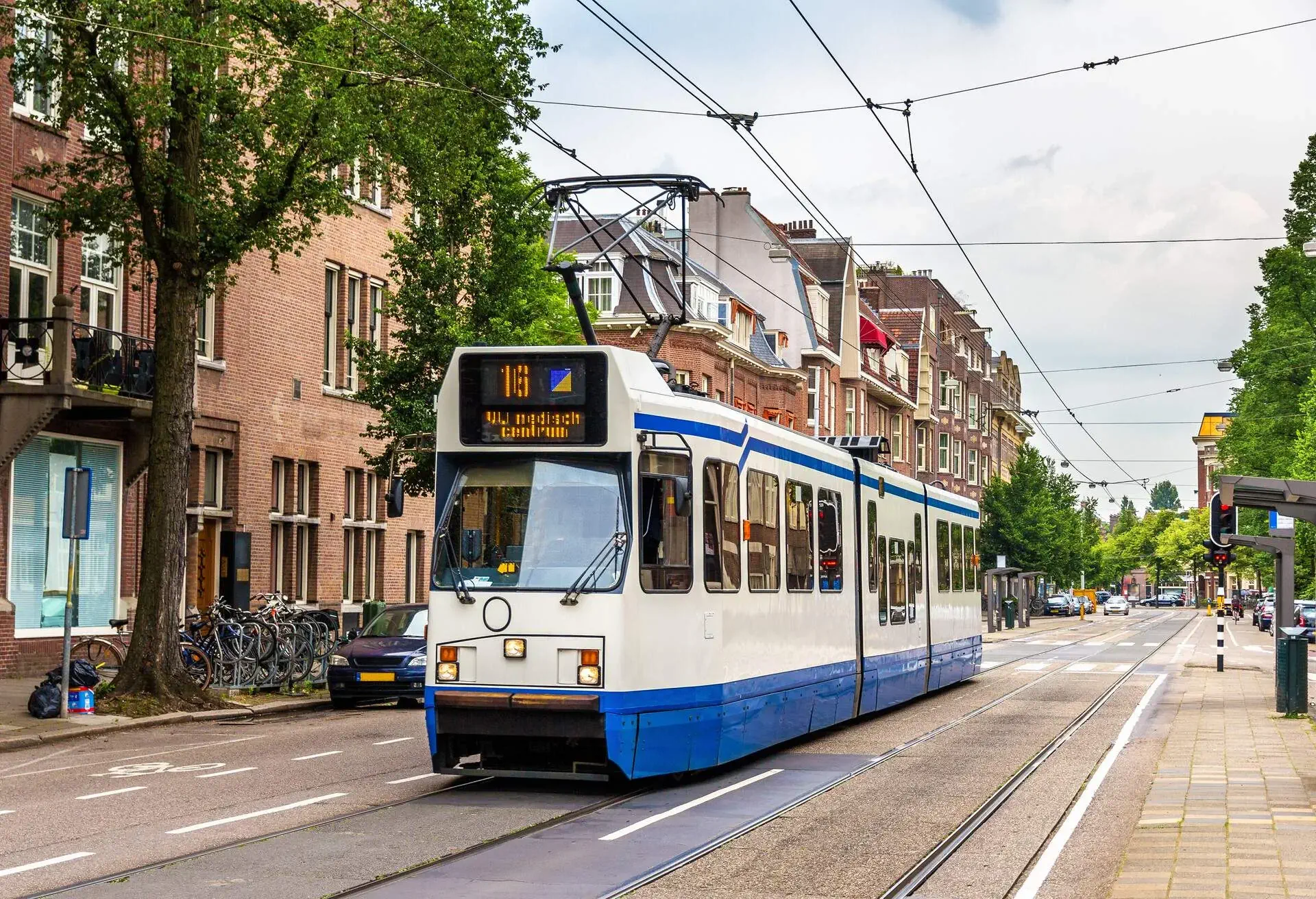 A tram passing through a city with redbrick buildings.