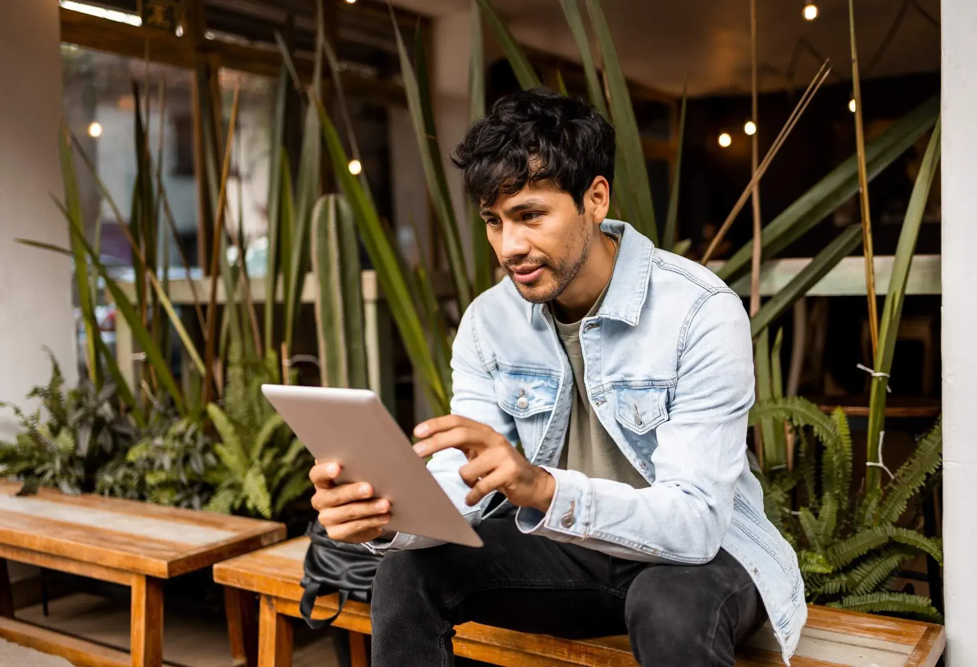 Man sat in a cafe looking at iPad device