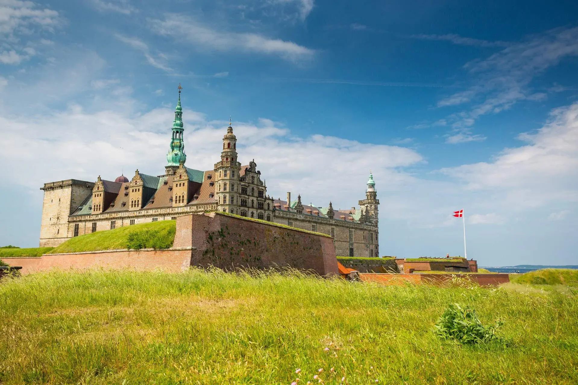 View of a castle surrounded by the sea and a field