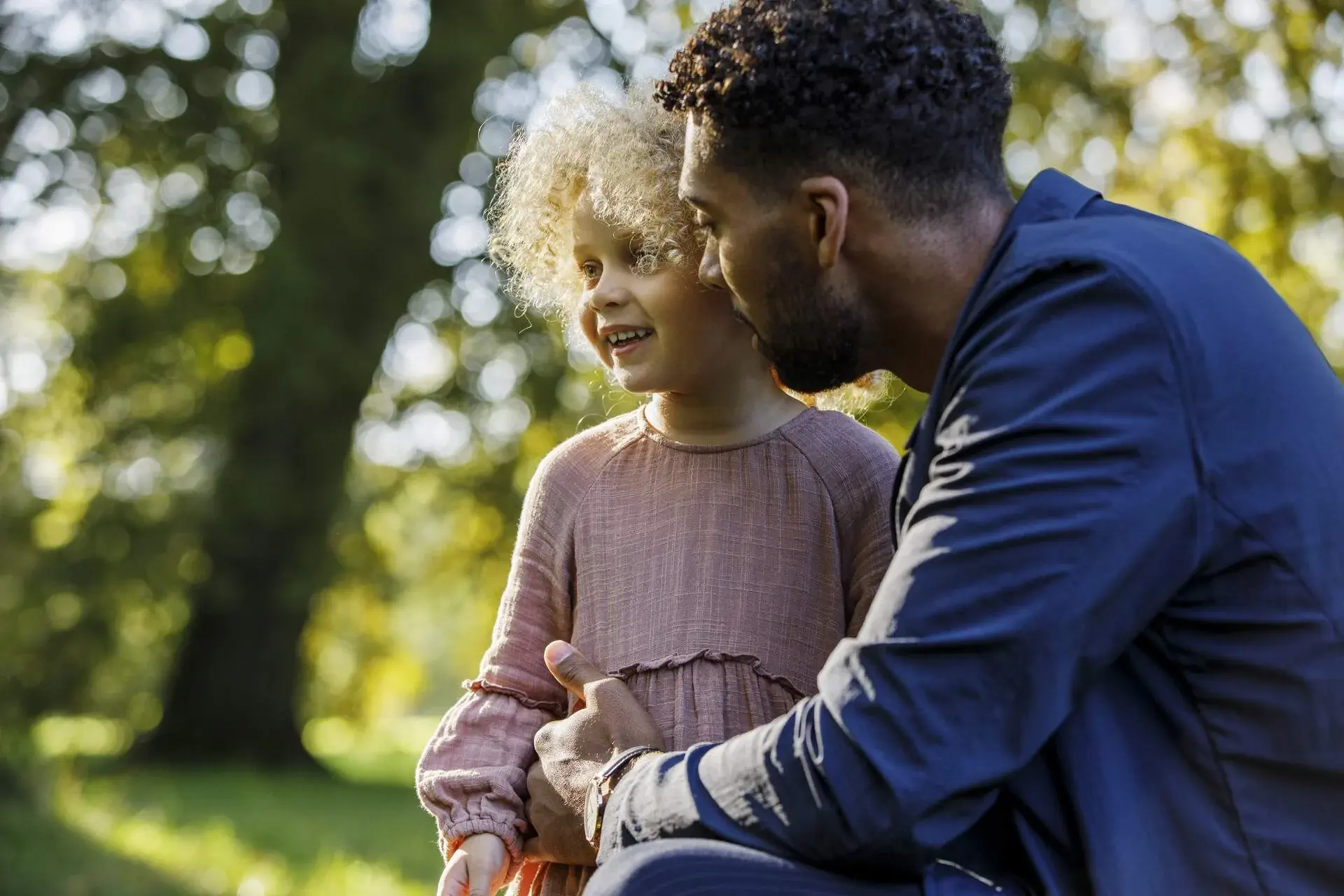 A father with his beautiful blonde afro daughter in the park.