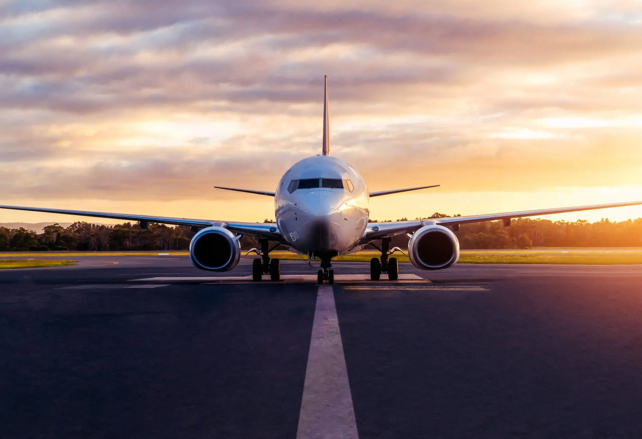 An airplane taxiing on a runway as the sky begins to darken at sunset.