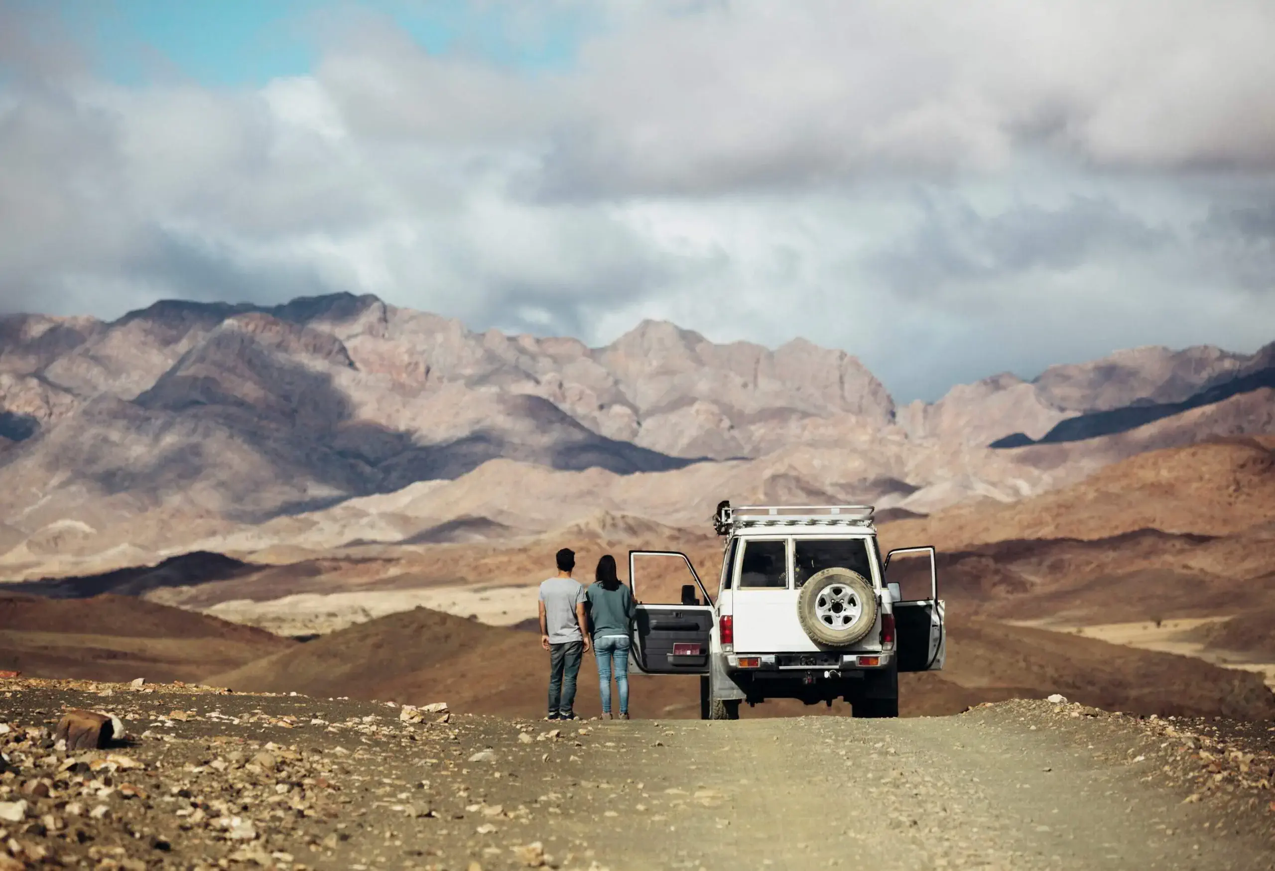 Two people standing next to a 4x4 in a desert