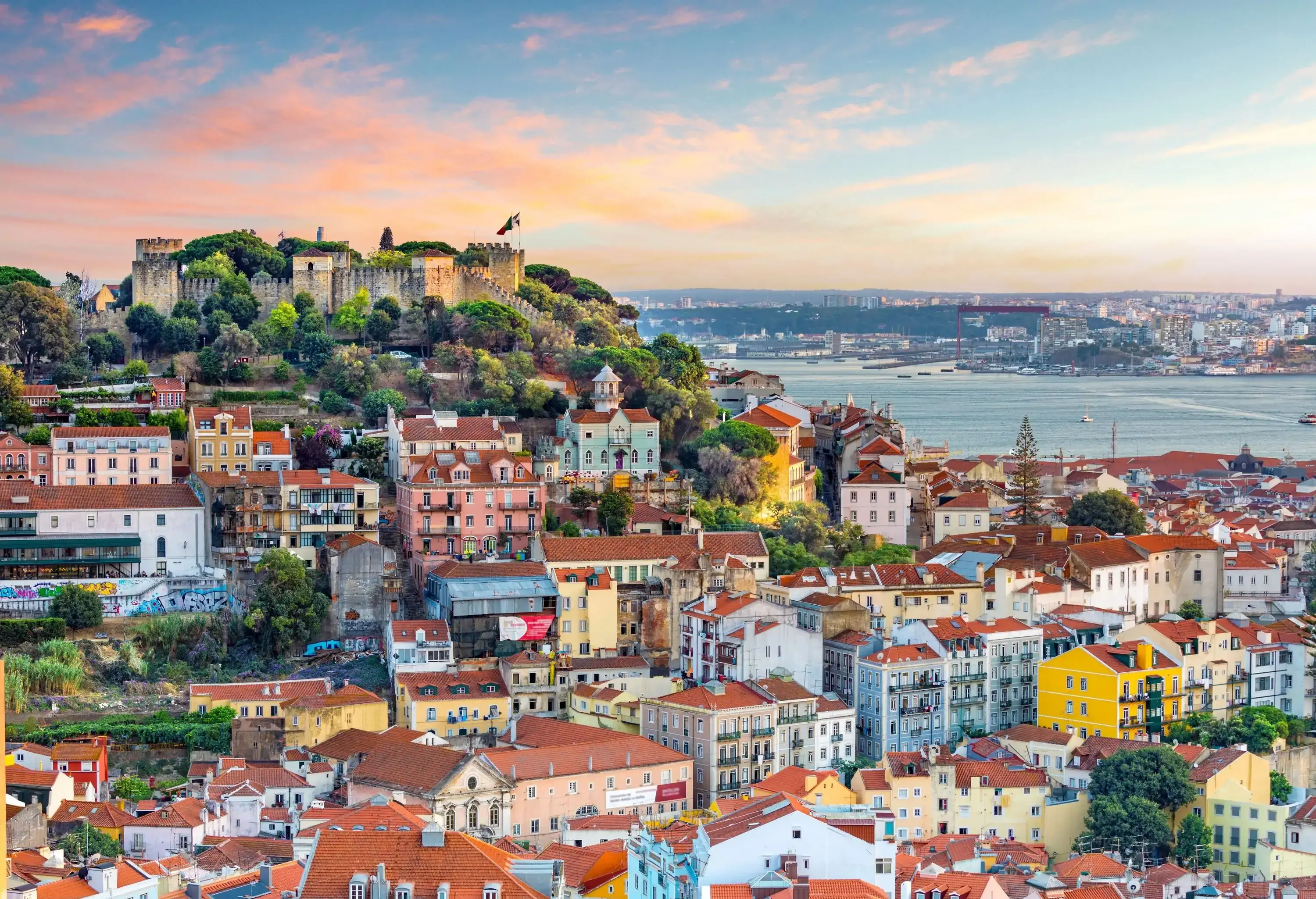 São Jorge Castle is a hilltop stone castle overlooking the urban landscape of a coastal city.