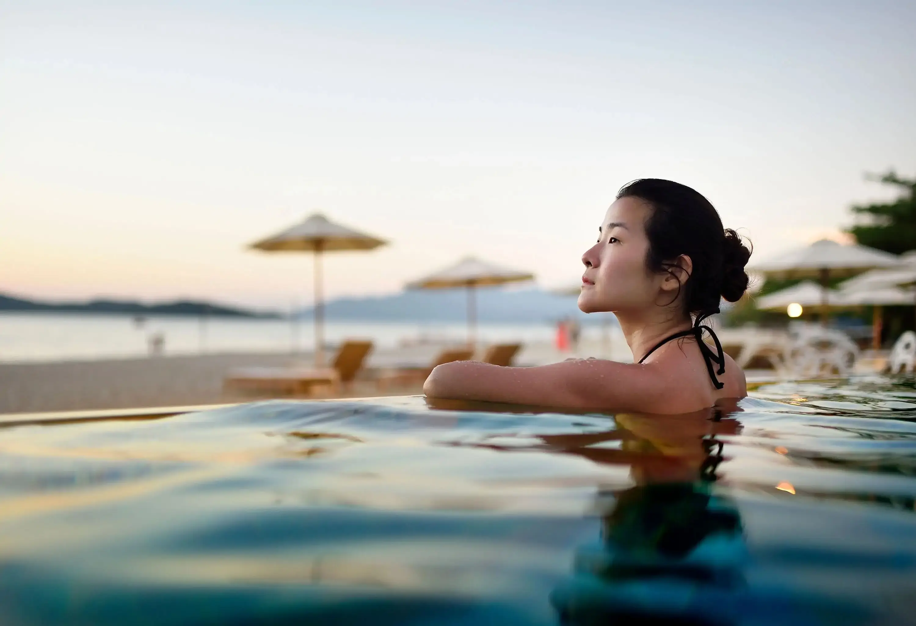 Asian woman in a resort pool at sunset