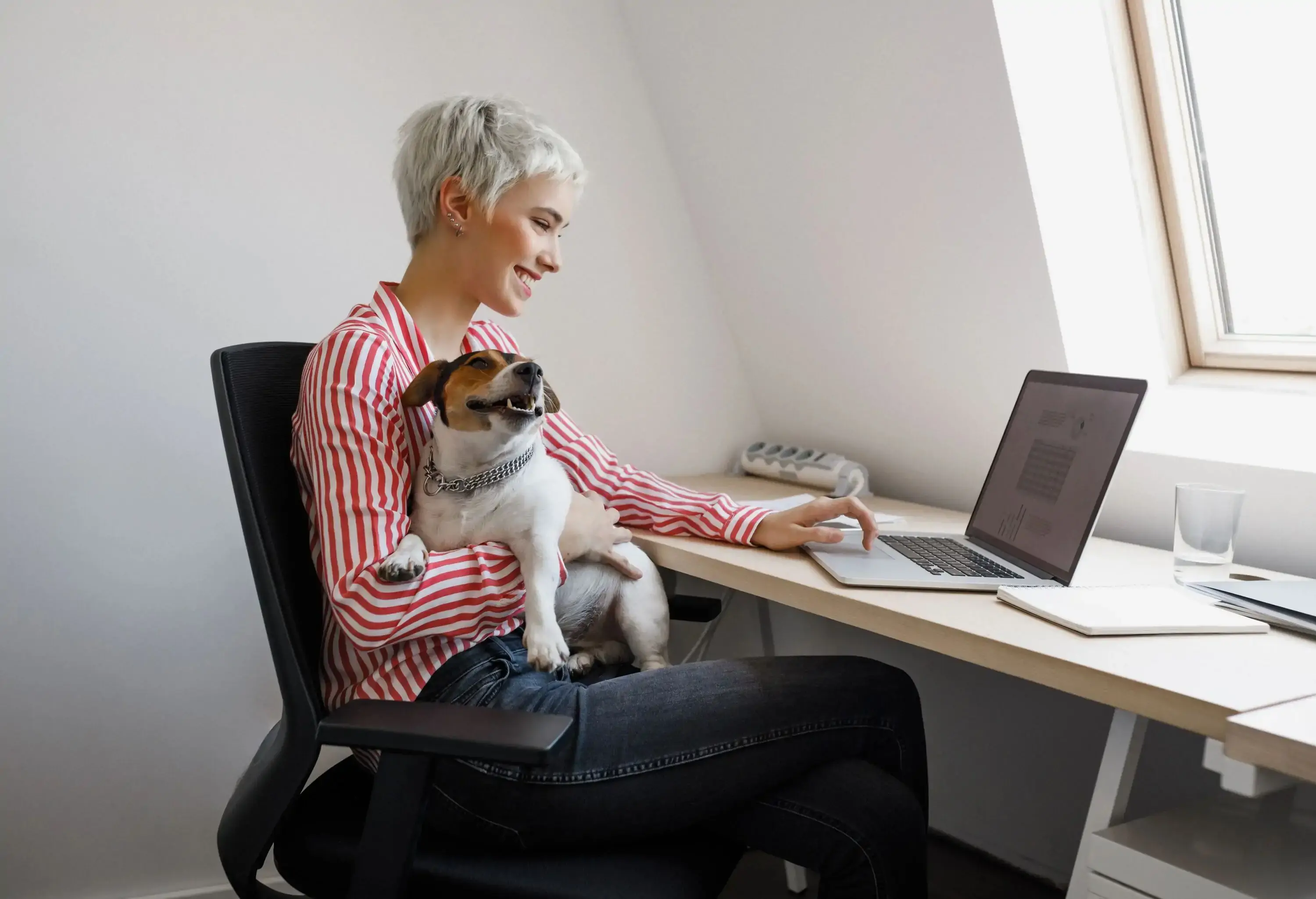 Young smiling businesswoman cuddling her dog pet at her office.