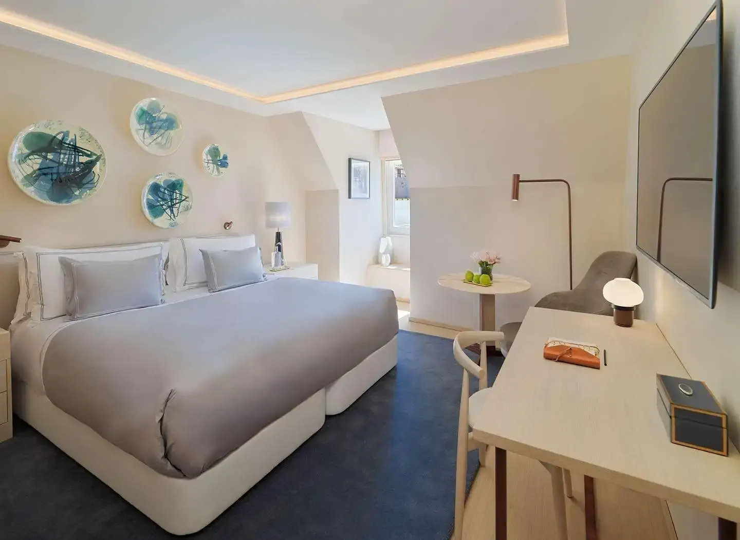 A brught hotel room featuring a comfortable bed, a desk for work, and a television for entertainment.