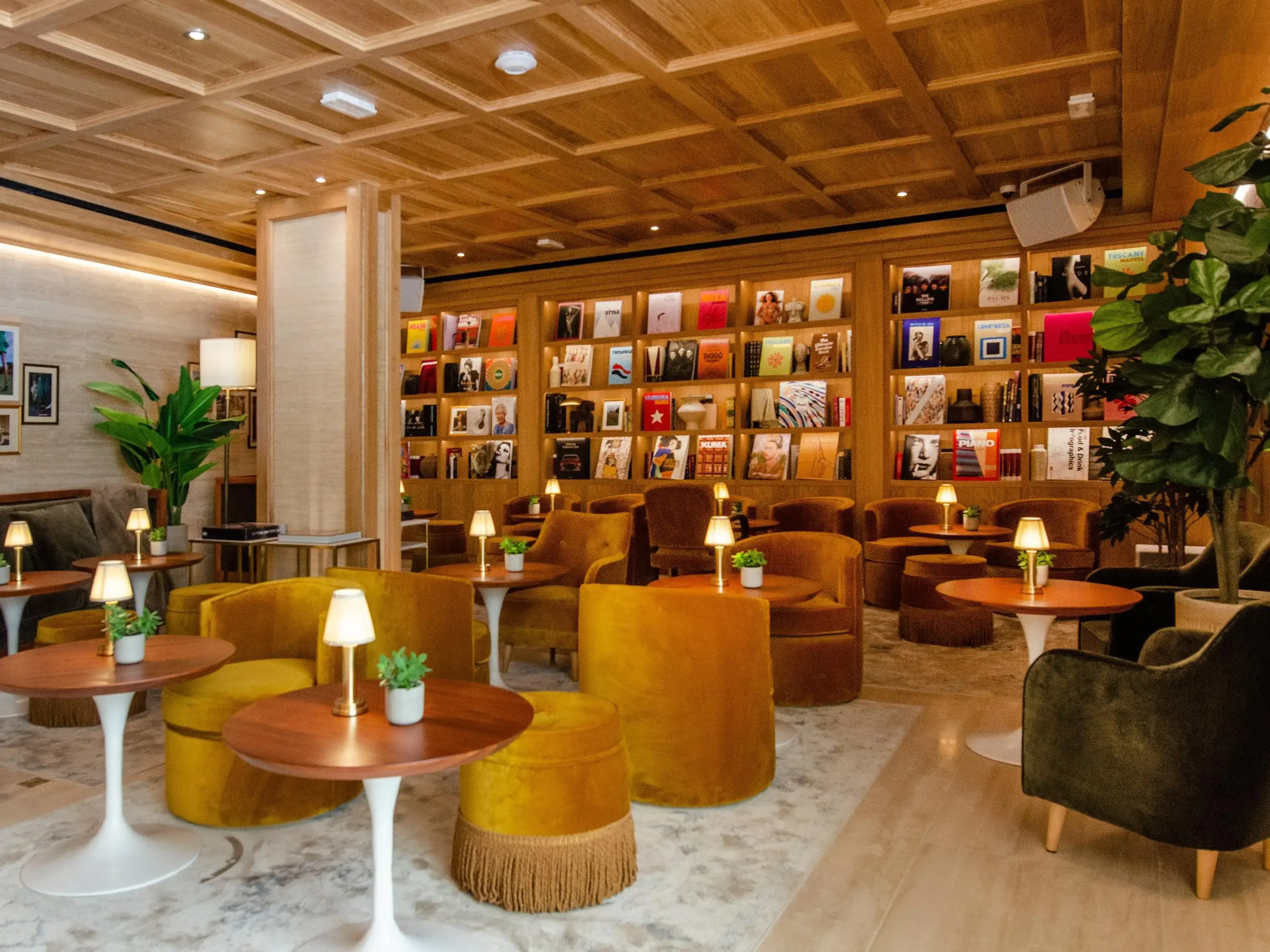 a stylish bar with velvet chairs and a library on the wall