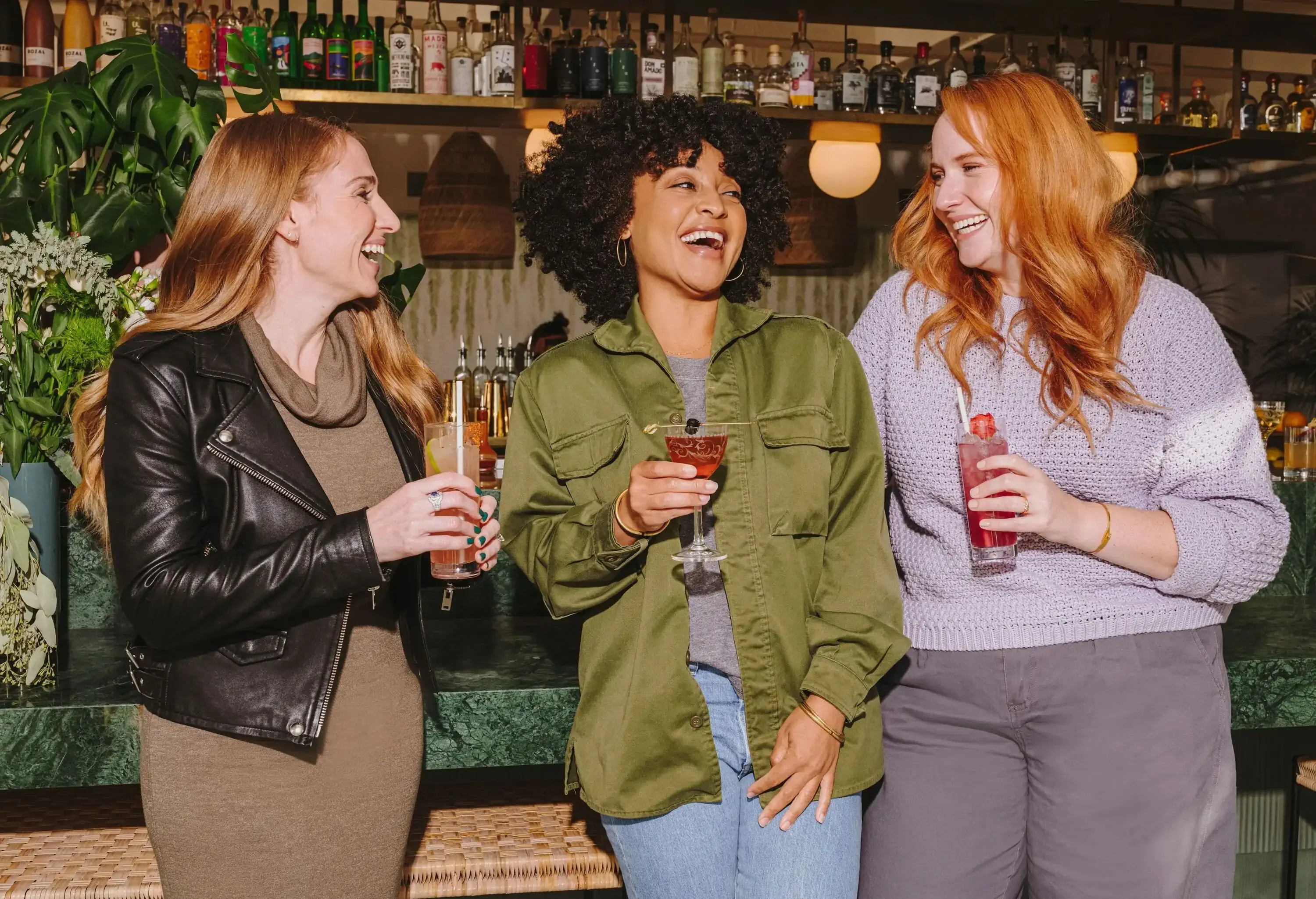 A group of ladies laughing while having a great time drinking in a bar.