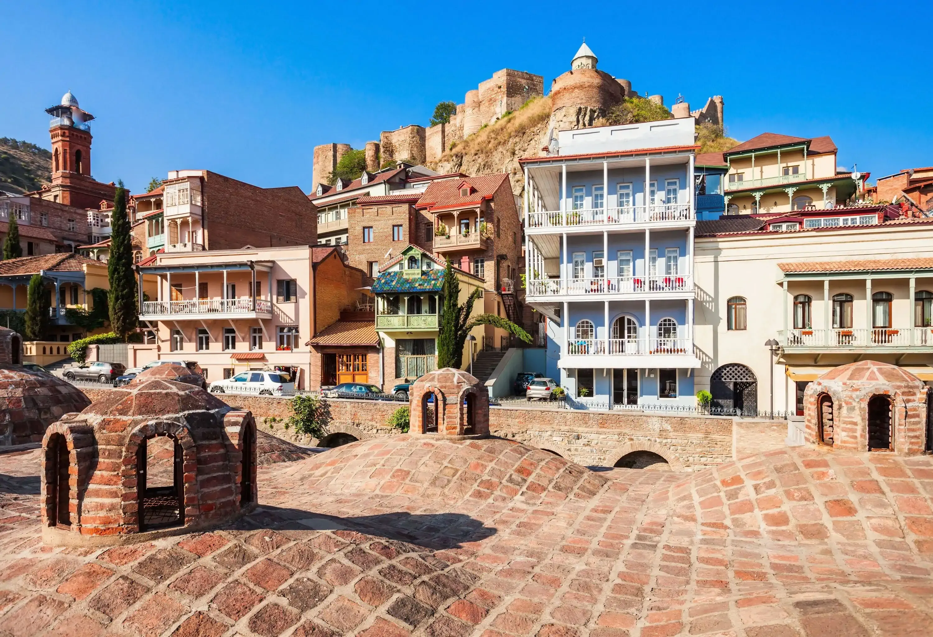 A wavy brick ground leads the way, accentuated by a charming, tiny brick pavilion nestled against a line of buildings.