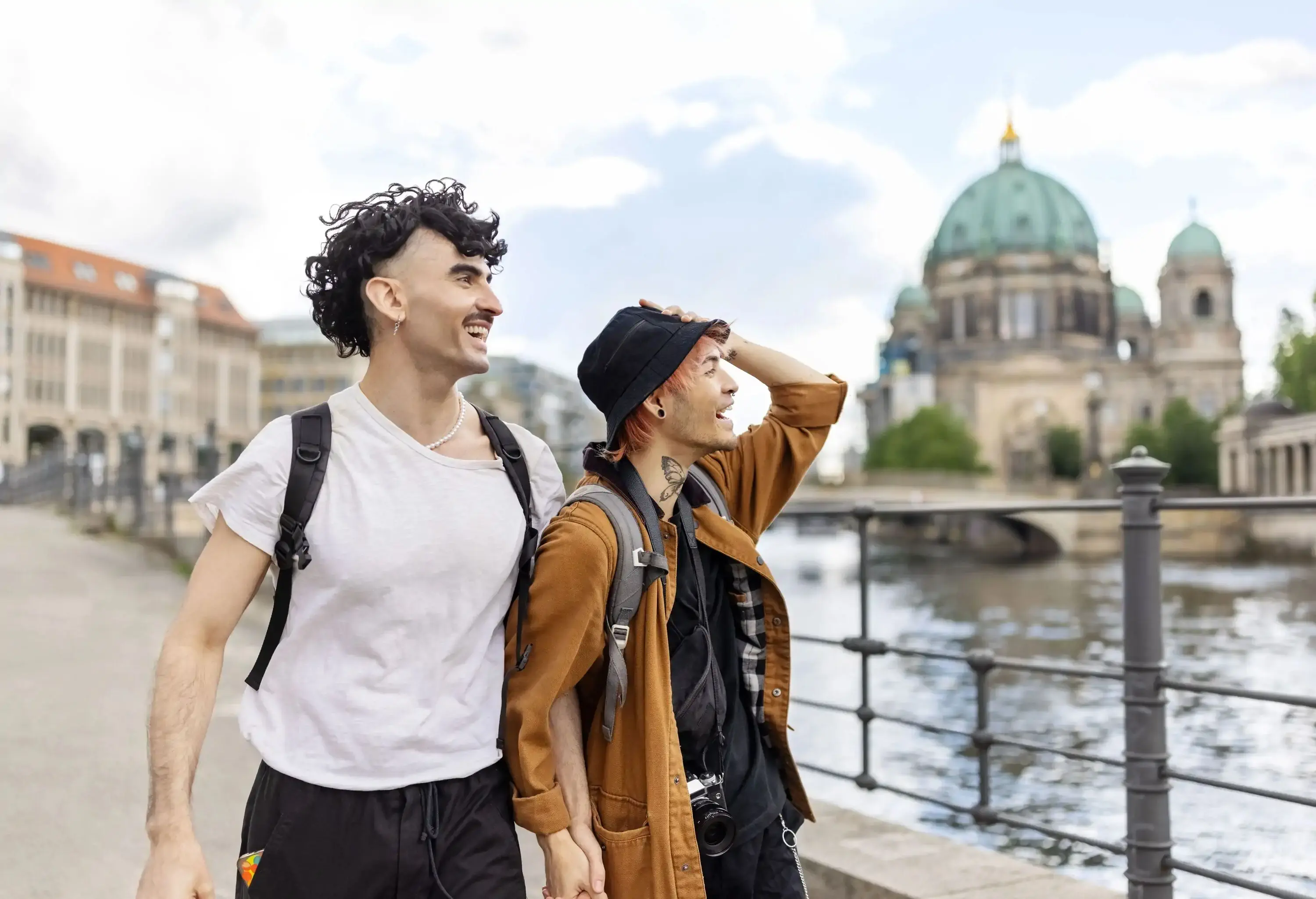 Cheerful gay couple leisurely walking together in a foreign city. Young men enjoying their vacation in foreign city.
