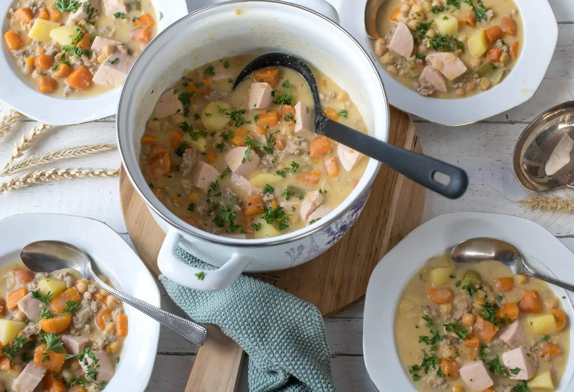 Homemade fresh cooked stew or soup with minced meat, vegetables, sausage, potatoes and chickpeas. Served on a kitchen table as a family meal . Ready to eat 