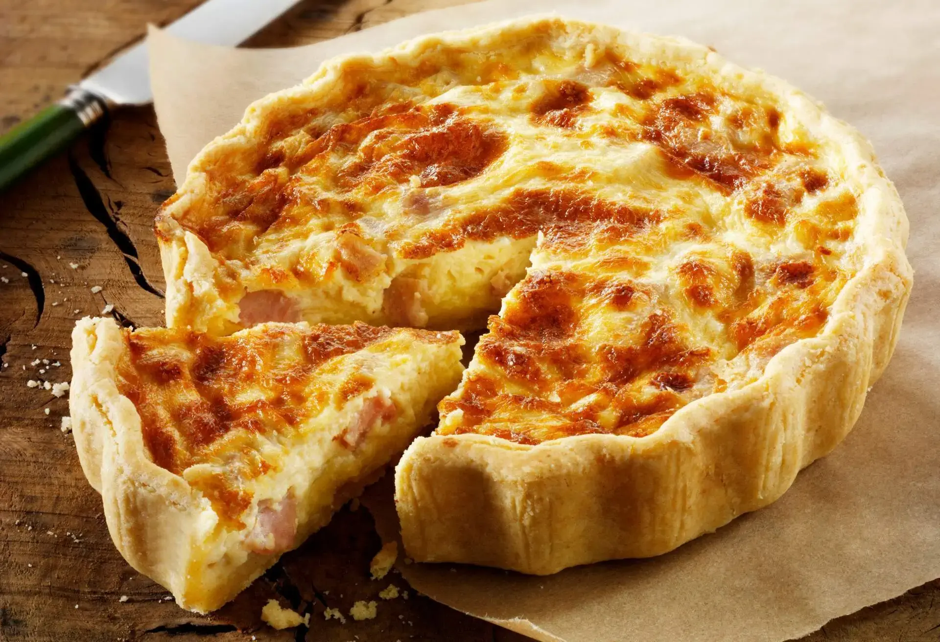 Quiche Lorraine with a slice cut on brown paper