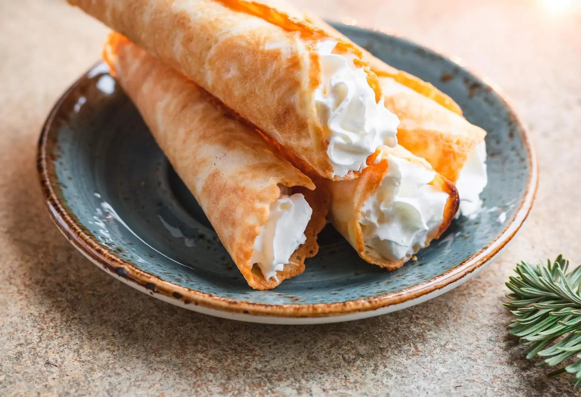 Traditional Christmas Norwegian cookies Krumkake with whipped cream among winter decor. 