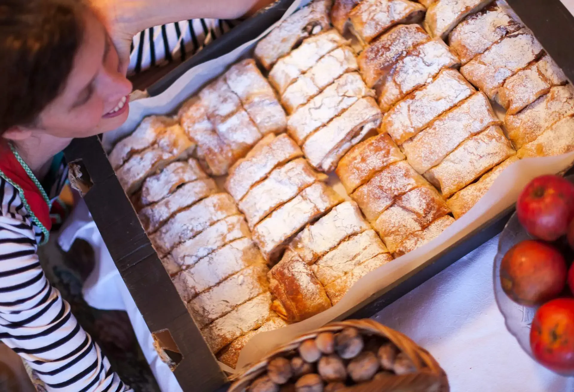 Woman holding backing tray with slices of Apfelstrudel