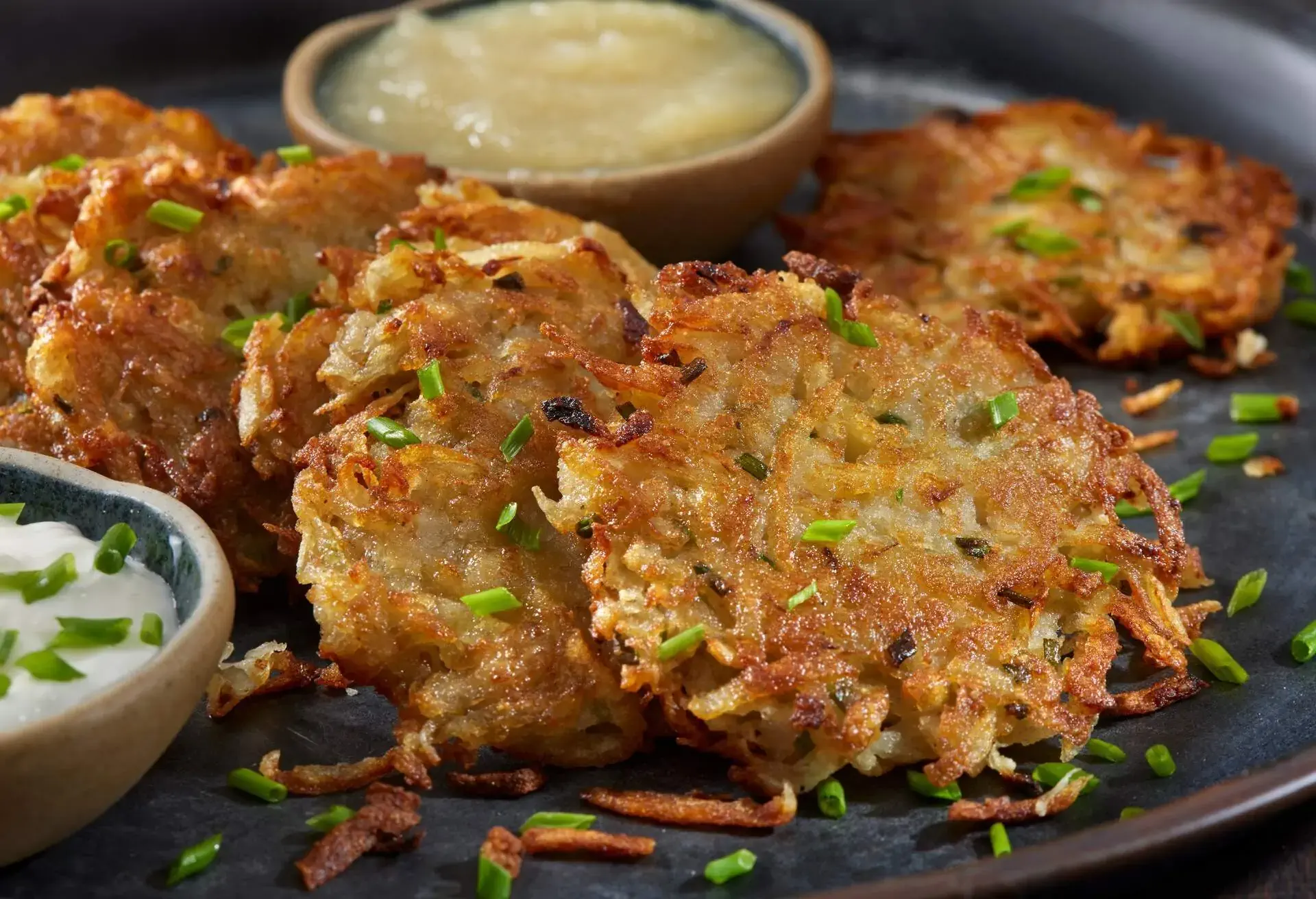 Black plate with Kartoffelpuffer and dipping sauces