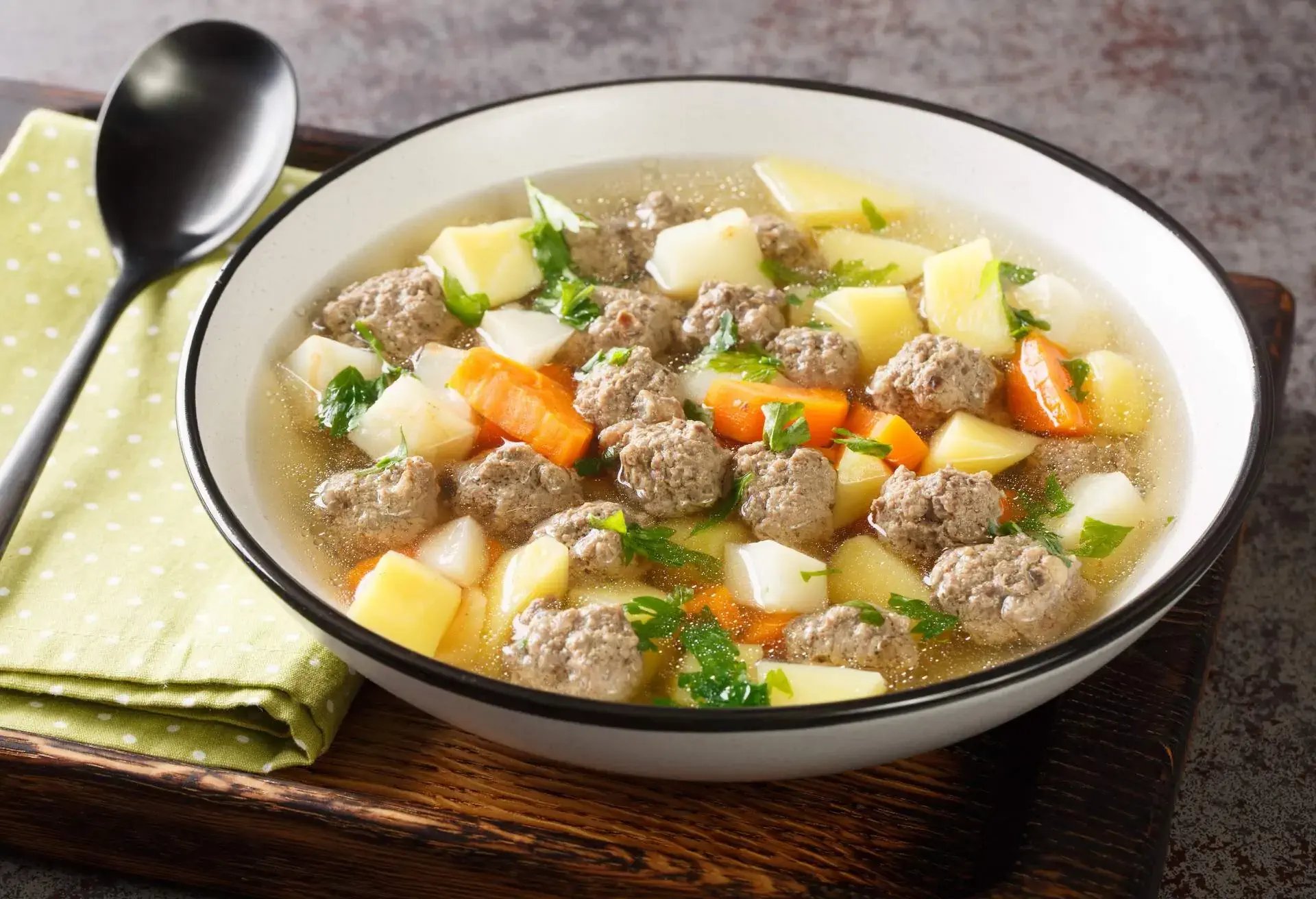 Sodd is a traditional Norwegian soup like meal with mutton, meatballs, potatoes and carrots closeup in the plate on the table. Horizontal 