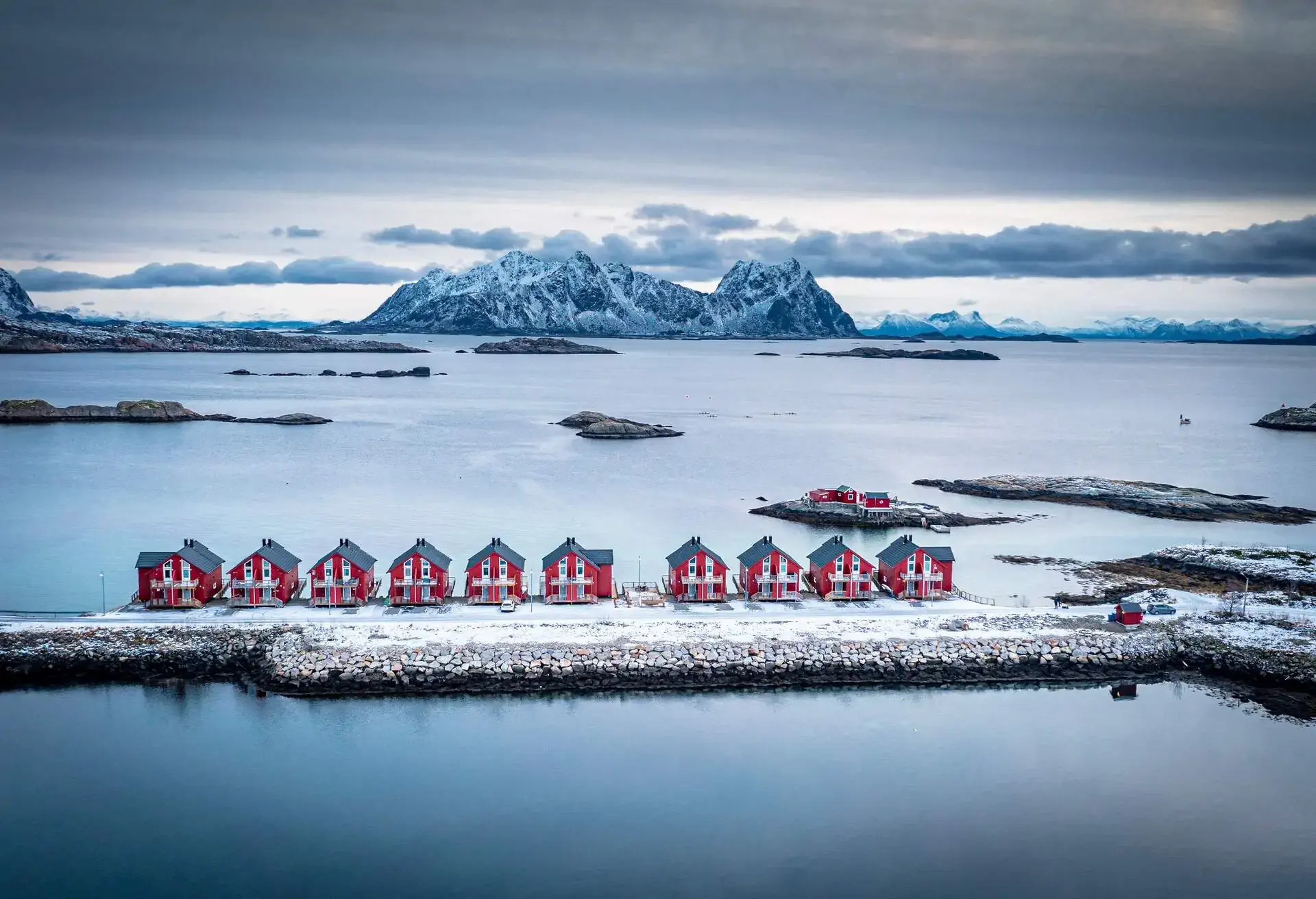 Snowcapped mountains and fisherman cabins along the frozen fjord, Svolvaer, Nordland, Lofoten Islands, Norway 