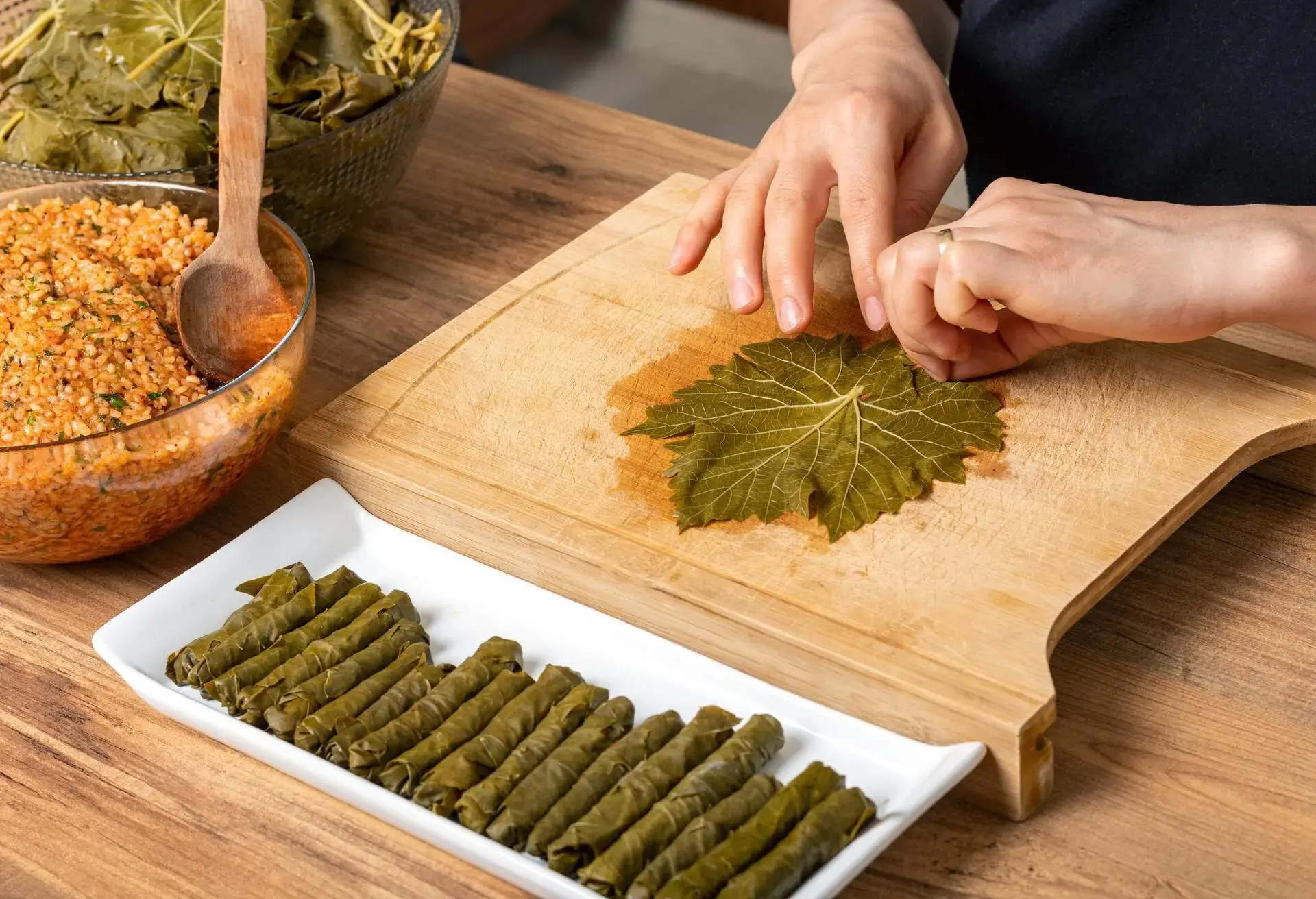 Woman's hands rolling up a vine leaf for dolmades
