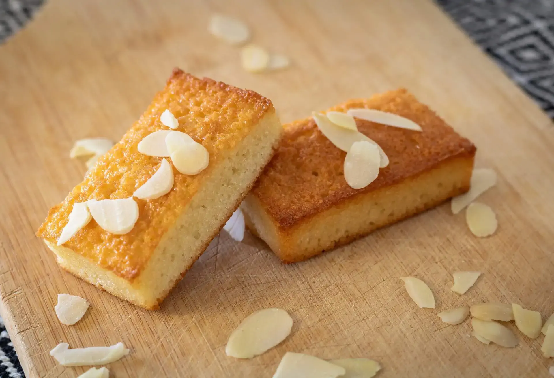 2 financiers on a wooden board with sliced almonds