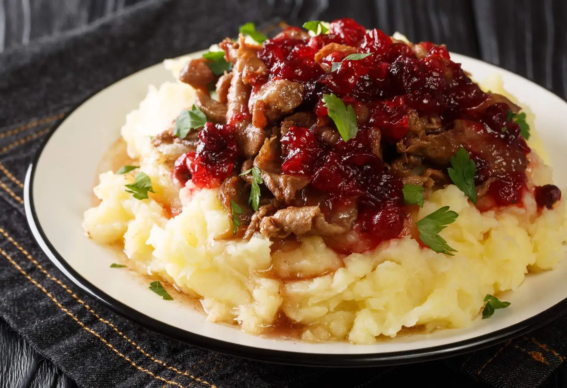 Lapland food Poronkaristys venison with mashed potatoes and lingonberry sauce close-up in a plate on the table. horizontal 