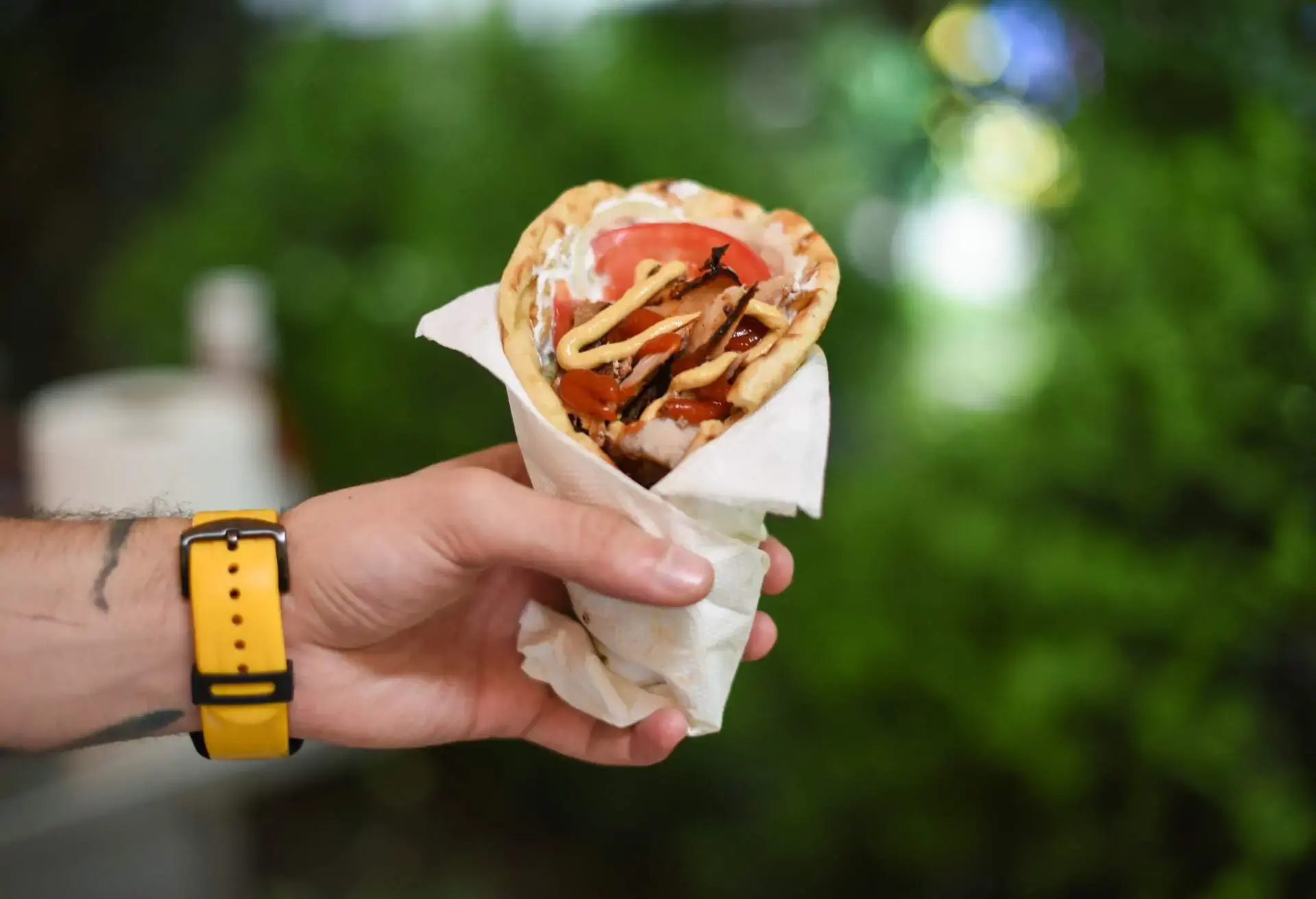 hand holding a gyros pita with Souvlaki and tomato