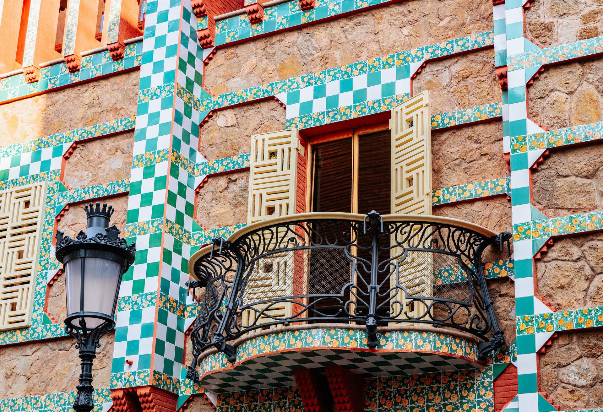 An window balcony attached to a brick wall decorated with ceramic tiles.