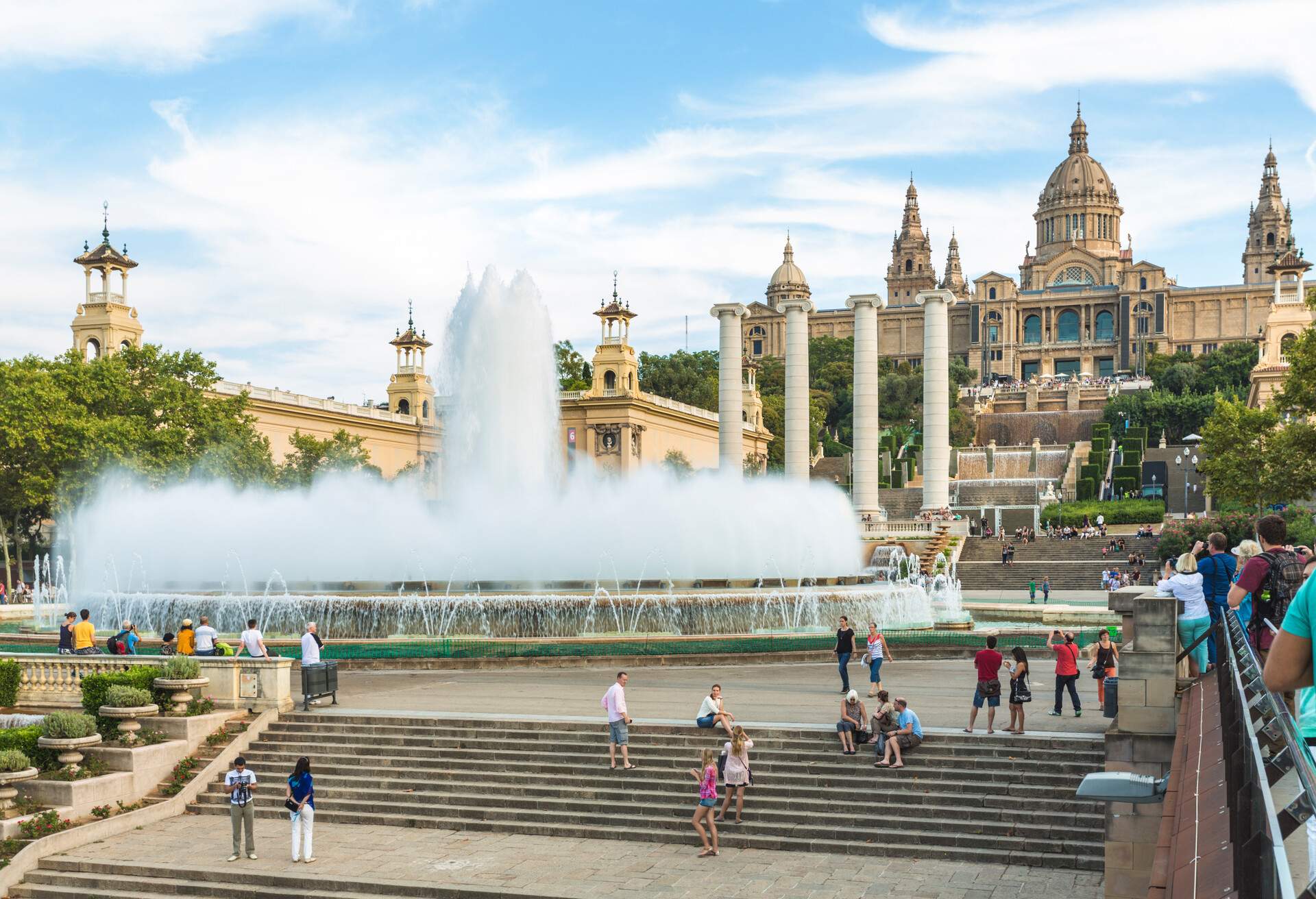 A grand architectural water fountain in a public square with an Italian-style building in the background.