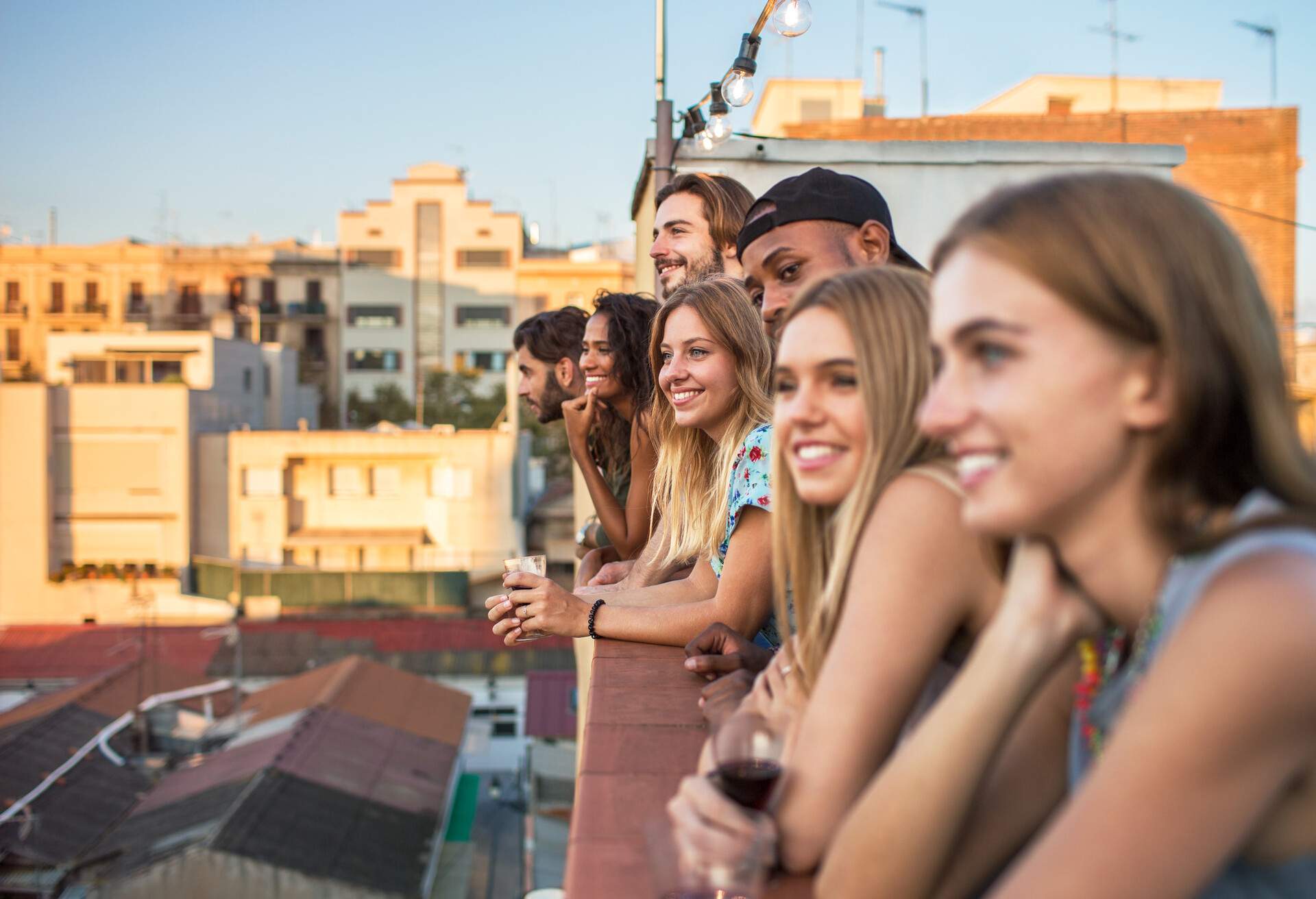 A circle of friends lined up on the rooftop overlooking the surrounding houses.