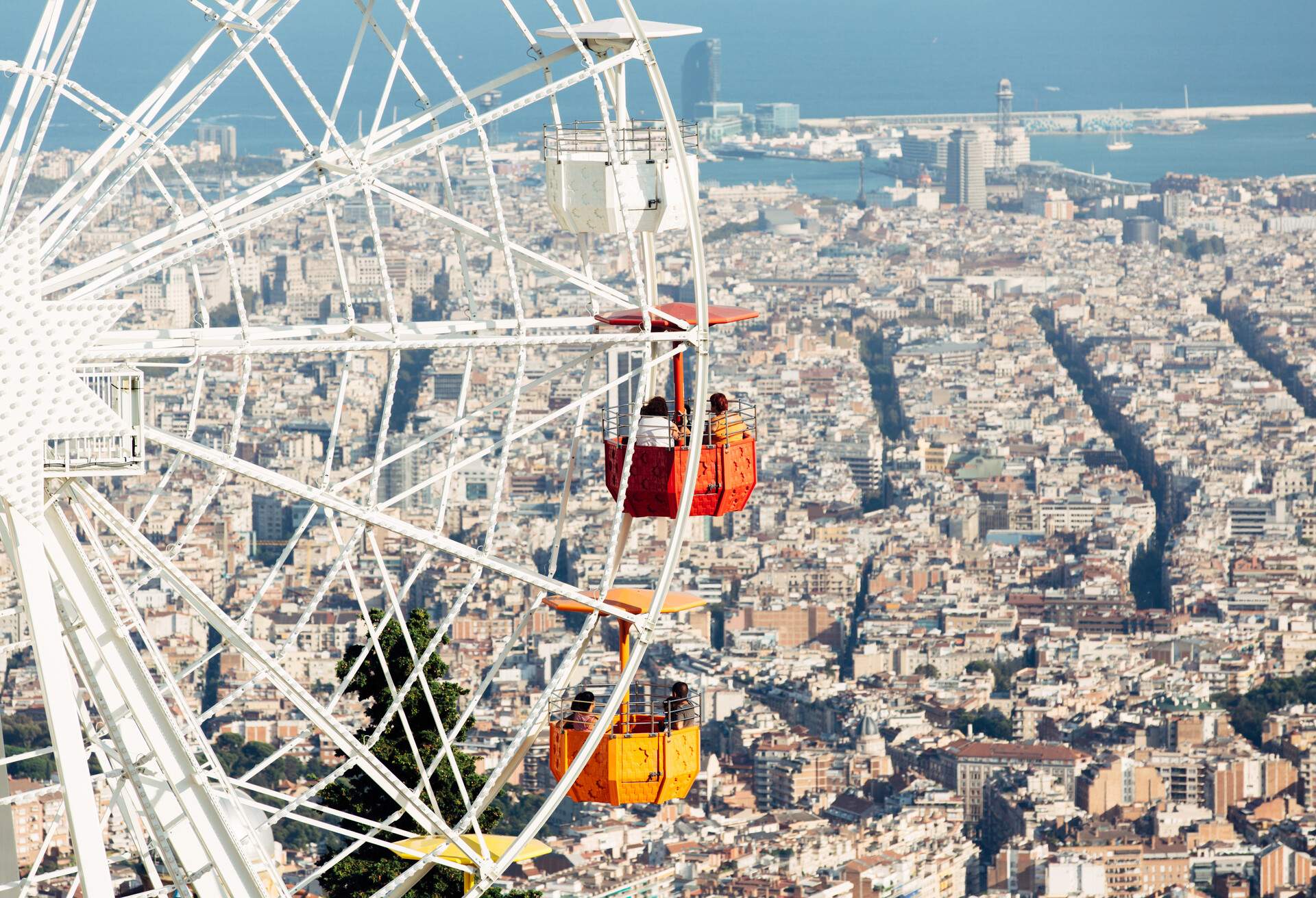 A Ferris wheel ride overlooking the skyscrapers in the city and the sea in the distance.