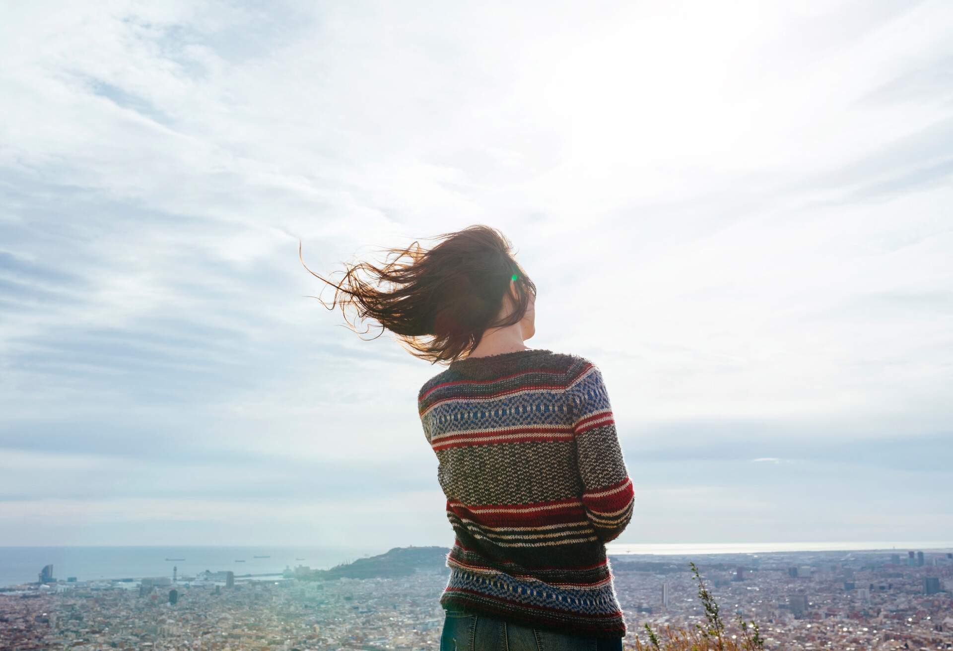 A woman enjoying the views of the city from a windy viewpoint.