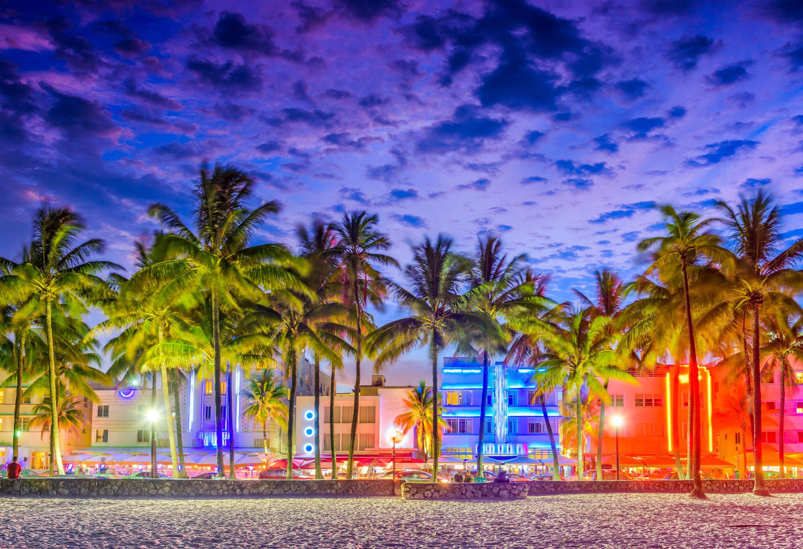 A row of buildings comes alive with a vibrant display of neon lights, casting a mesmerizing glow under the scenic purple twilight sky. 