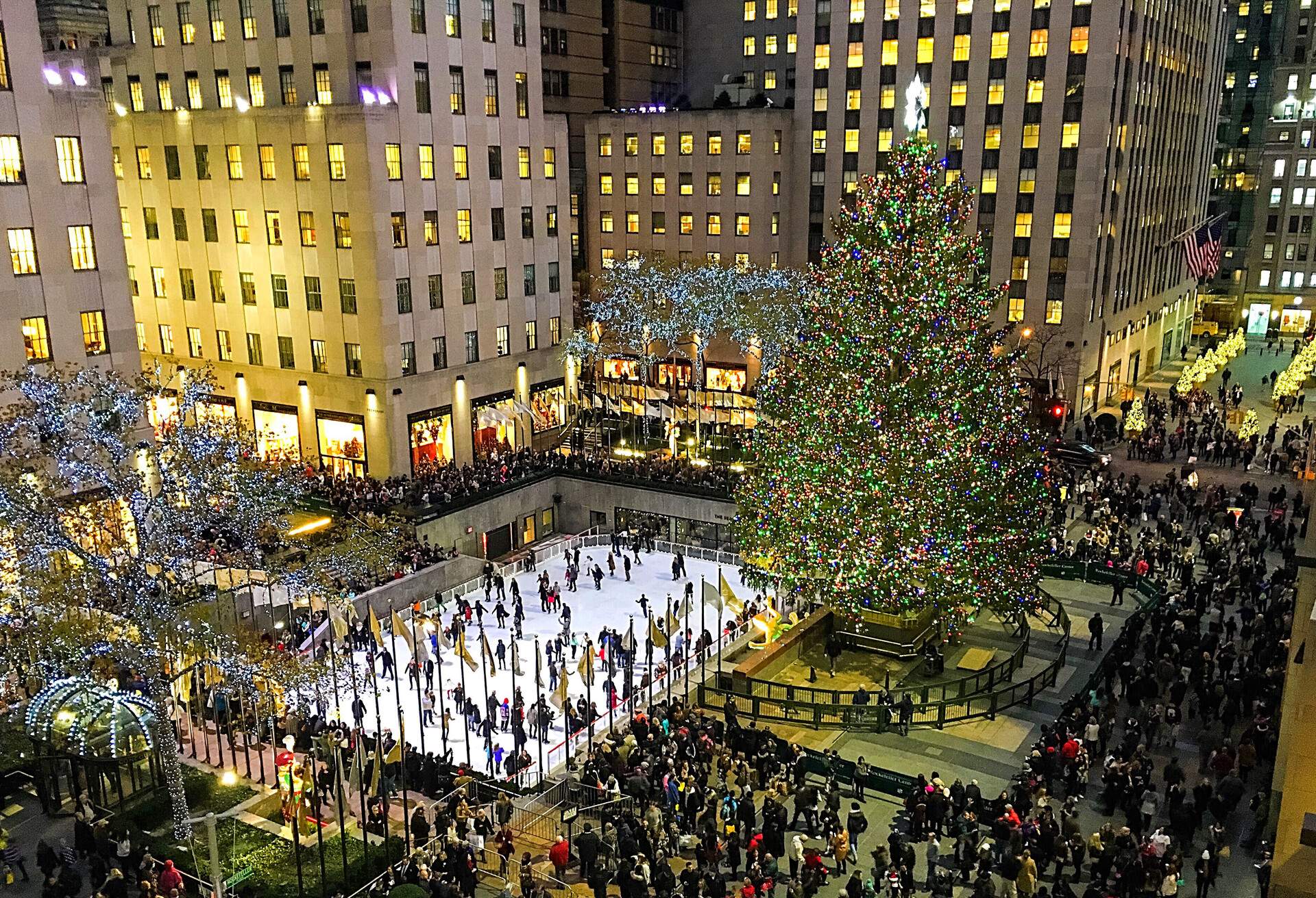 The Rockefeller Centre crowded with people during the holidays with its iconic Christmas tree lit up at night.