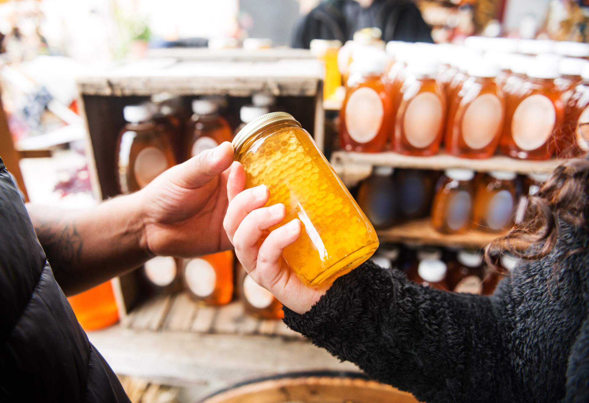 Two people buying a jar of honey at a local market.