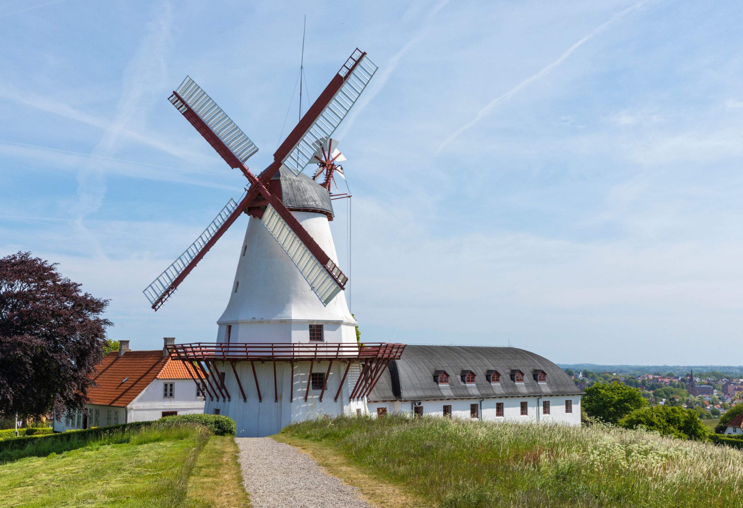 a white old windmill on top of a hill on a summer day
