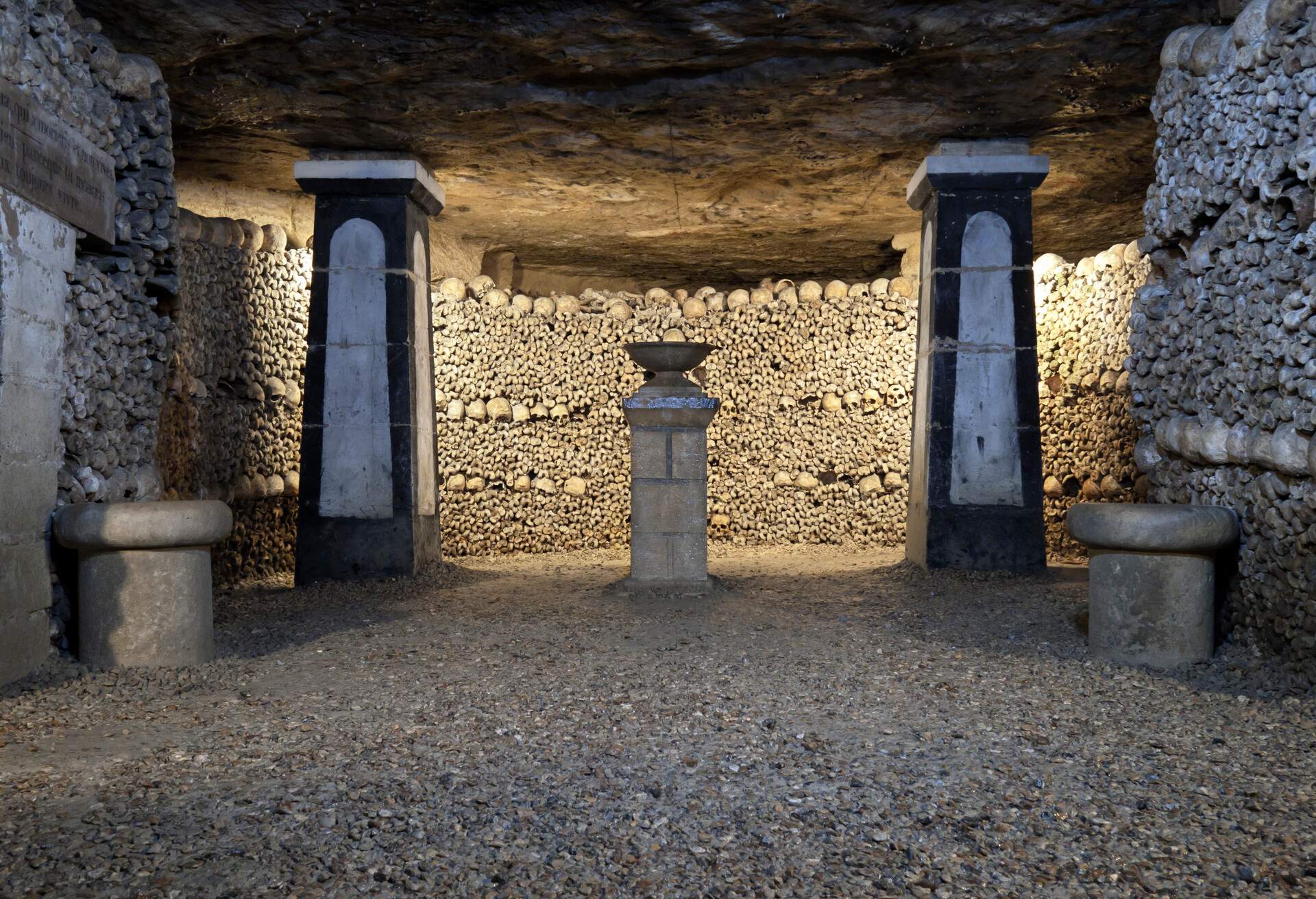 The inside of an underground ossuary with pillars and stacked human skulls and bones.
