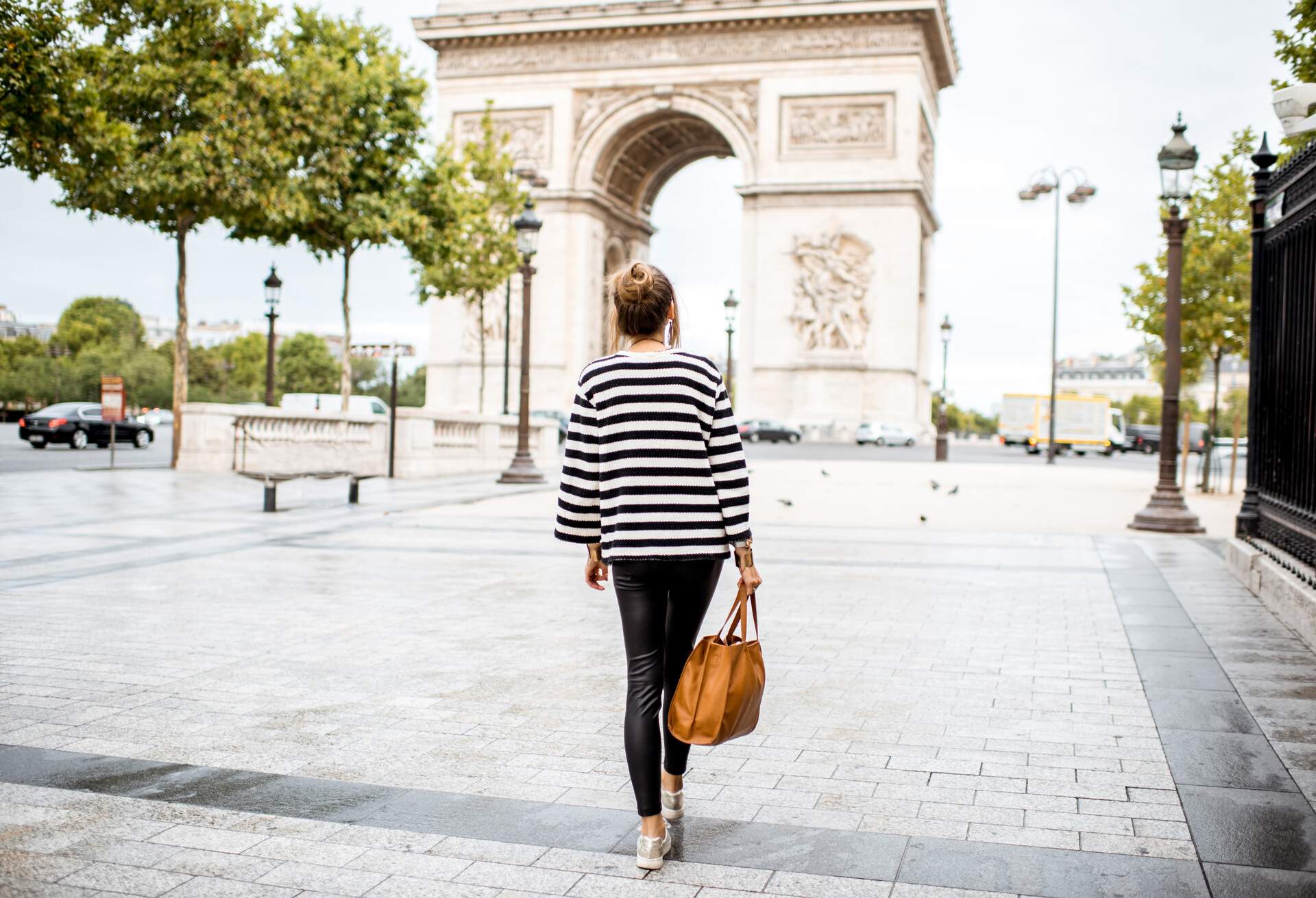 Lifestyle portrait of a young stylish business woman walking outdoors near the famous triumphal arch in Paris
