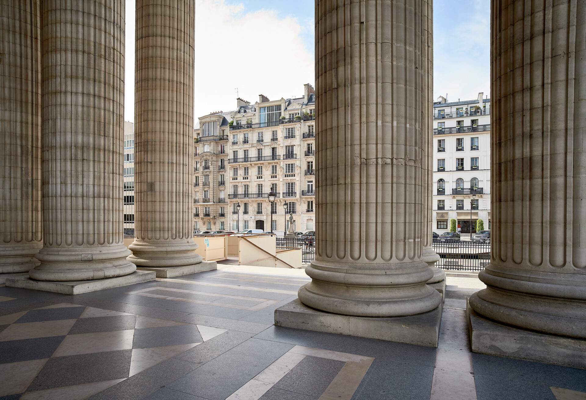 Massive ribbed columns standing on a stone tiled floor of a portico.