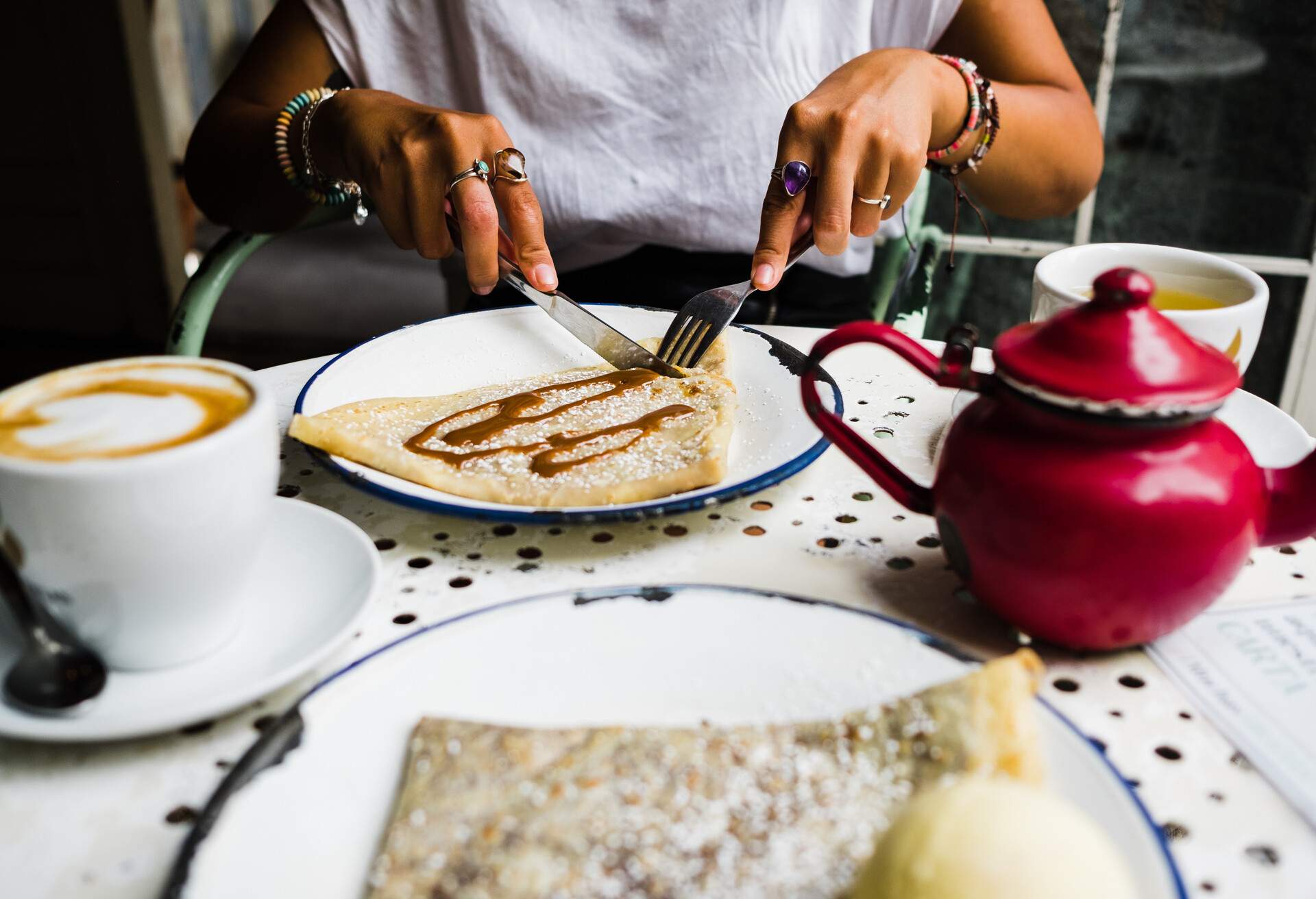 A woman eating crepe with a fork and knife.